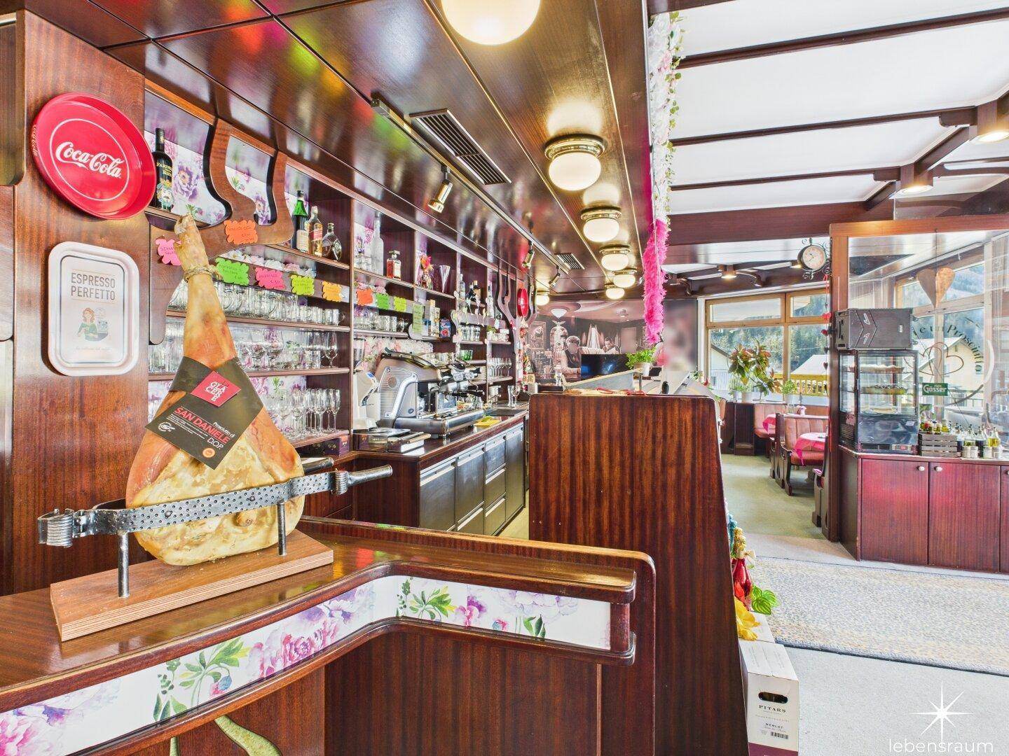 Nahaufnahme der Bar mit Schinken, Kaffeemaschine und einer Vielzahl von Gläsern und Flaschen.