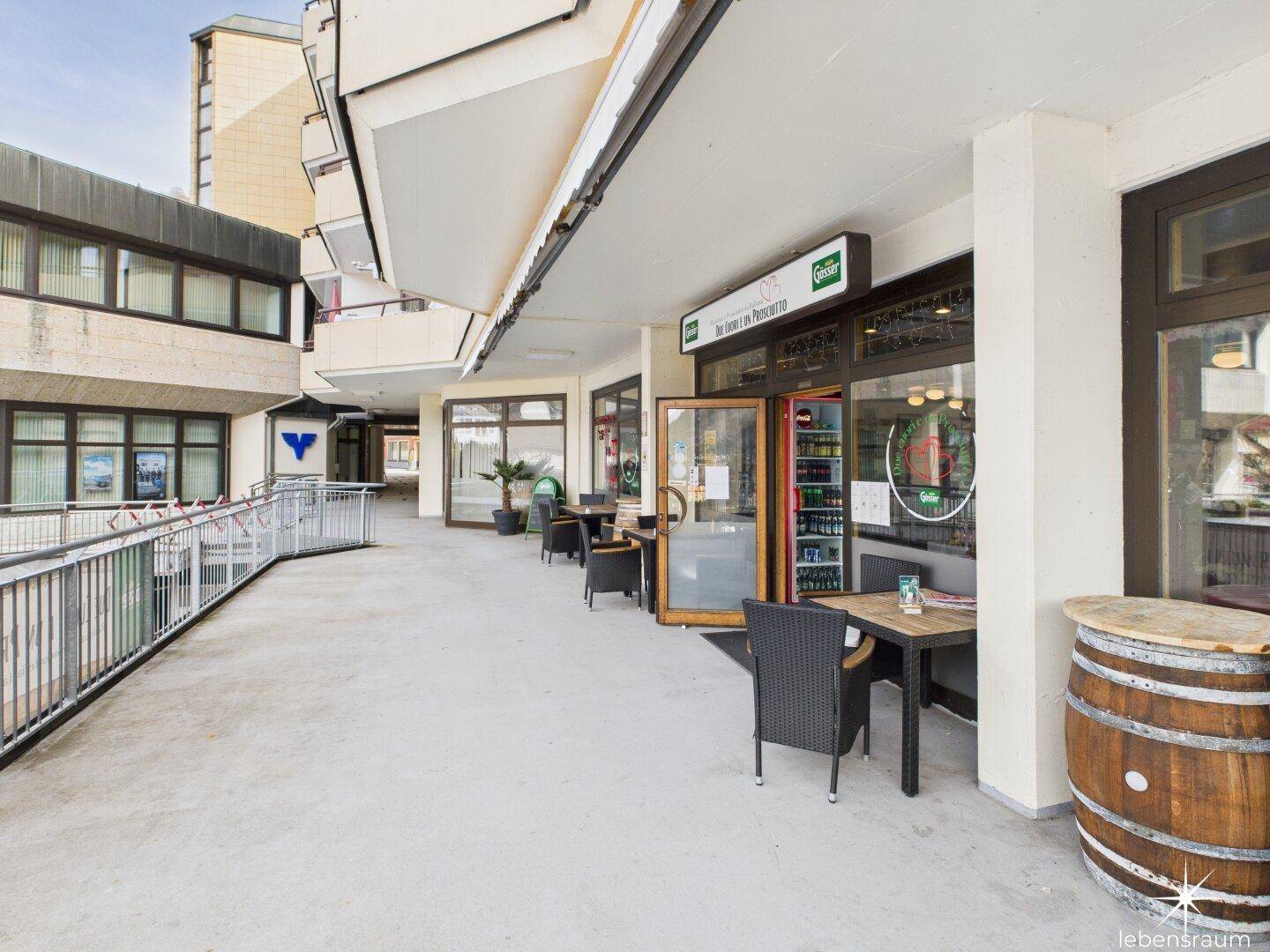 Lange Außenterrasse eines Restaurants mit Tischen, Stühlen und Blick auf die Umgebung.