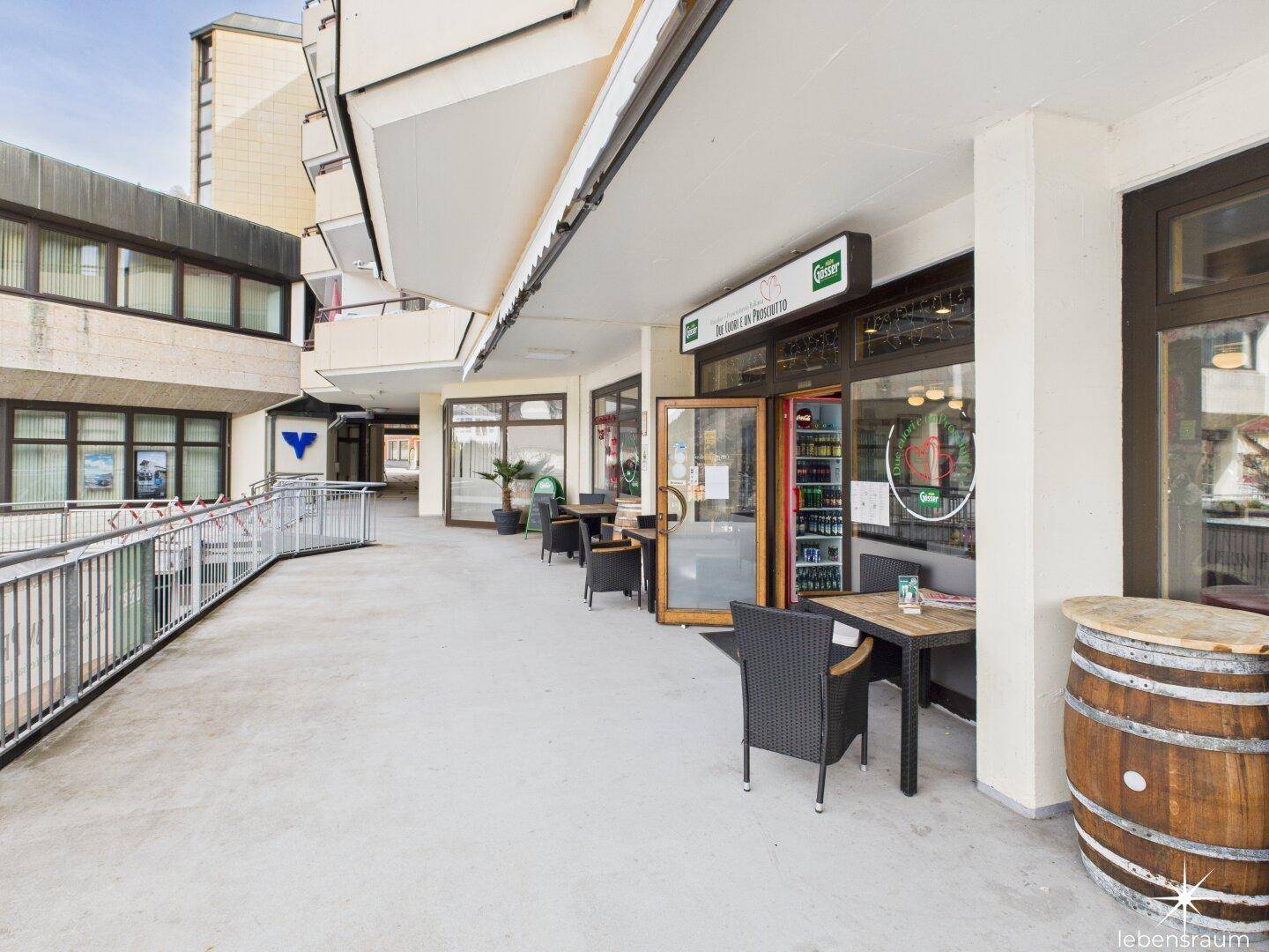 Lange Außenterrasse eines Restaurants mit Tischen, Stühlen und Blick auf die Umgebung.
