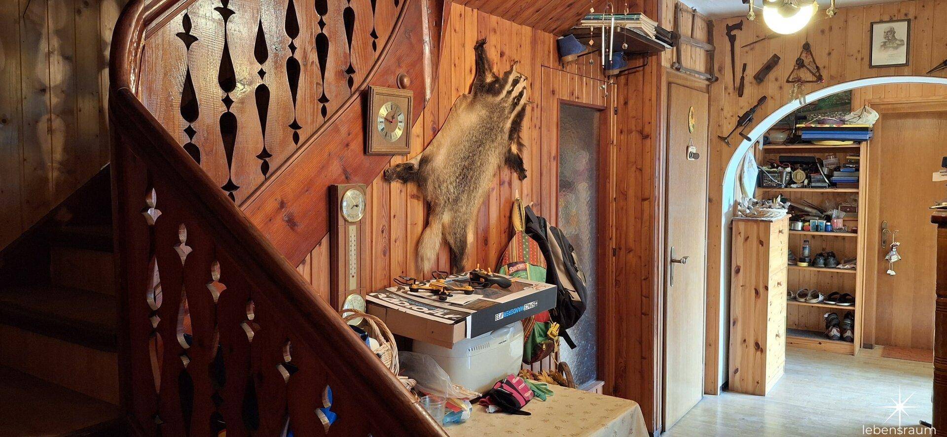 Holztreppe und Wandverkleidung im Flur mit rustikaler Dekoration und Tierpräparat.
