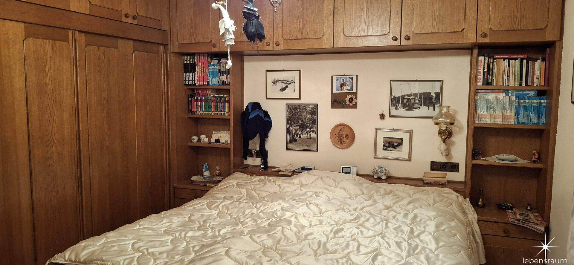 Schlafzimmer mit großem Bett und integrierten Holzschränken, bietet viel Stauraum.