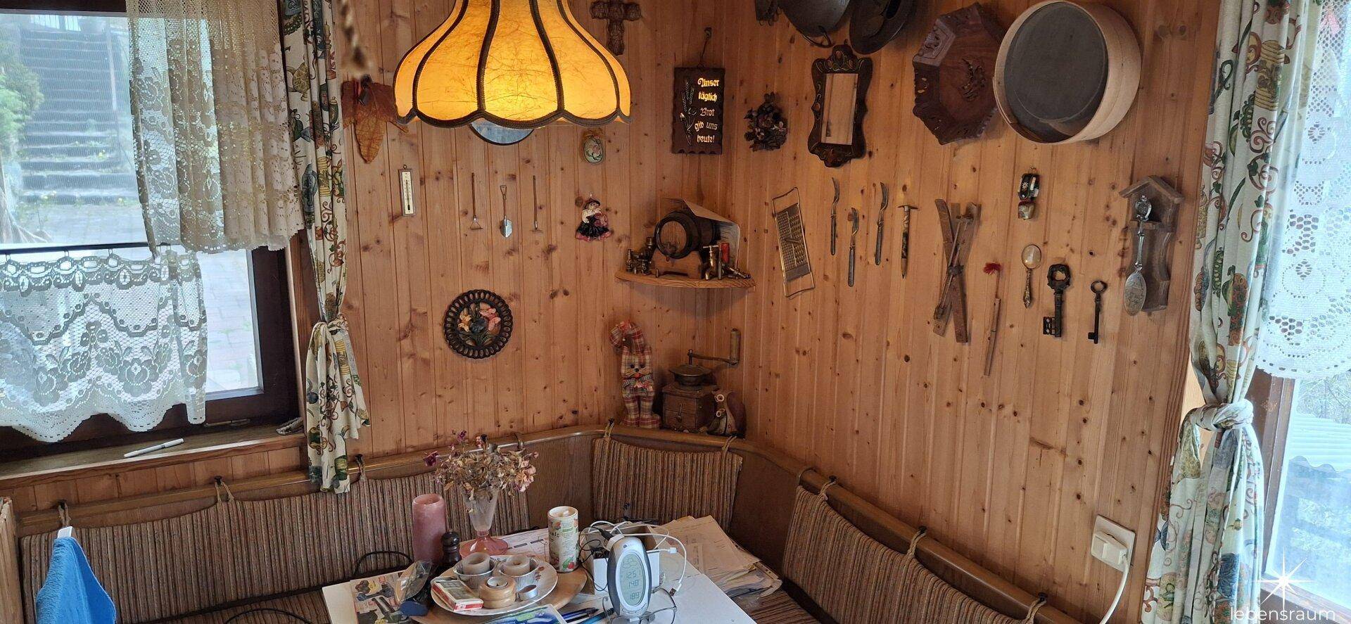 Gemütliche Essecke mit Holzvertäfelung und traditioneller Einrichtung, hell durch Fenster.