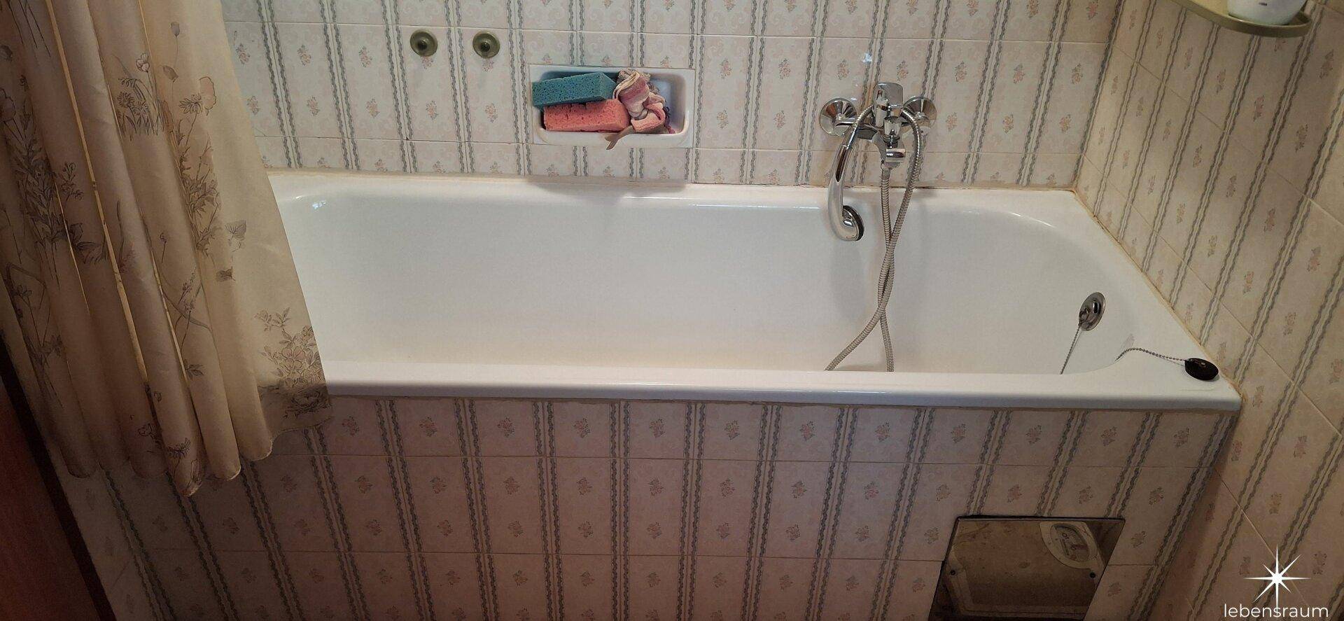 Badezimmer mit Badewanne und gefliesten Wänden, bereit für die tägliche Nutzung.