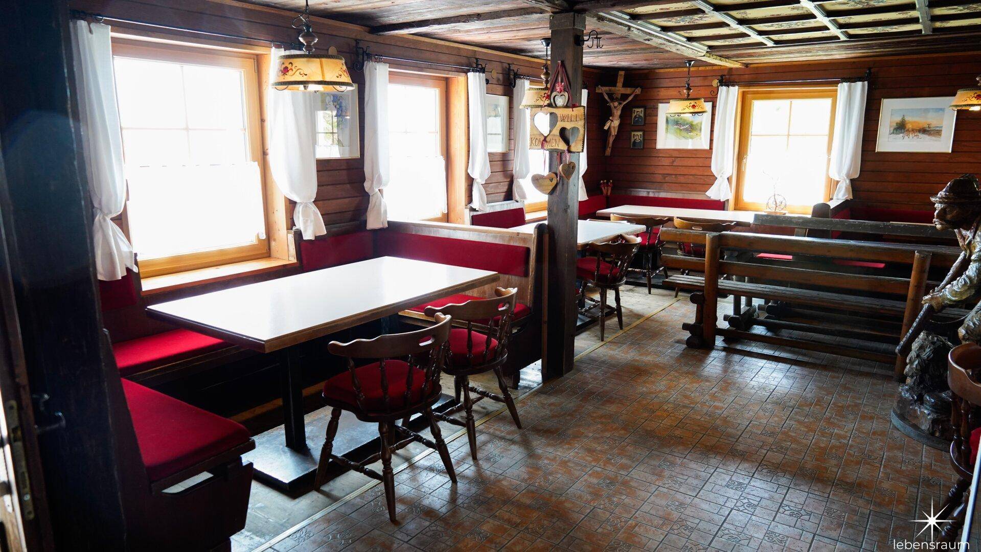 Traditioneller Wohn- und Essbereich mit Holzbänken, Tischen und rustikalem Charme.