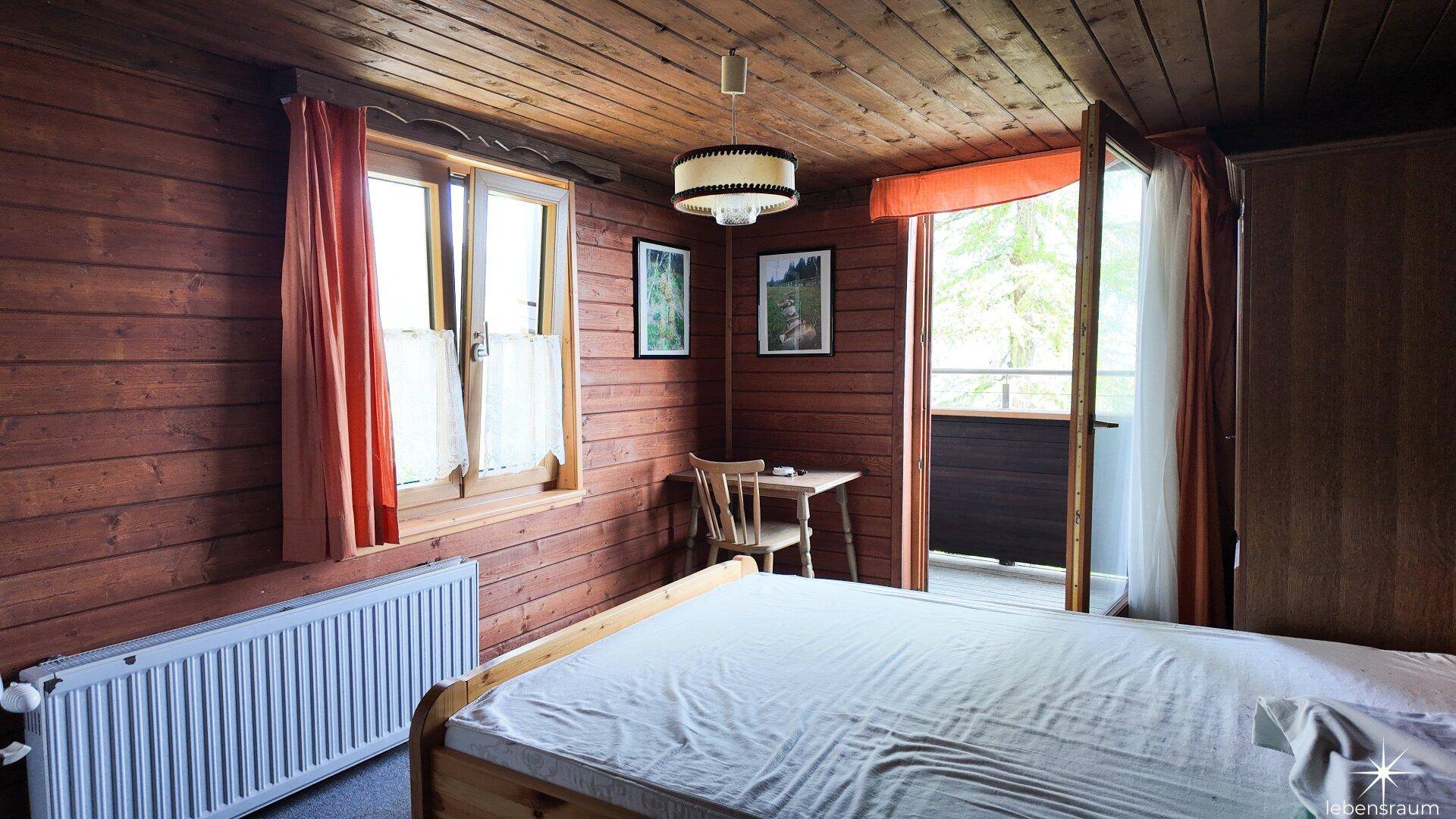 Schlafzimmer mit Holztäfelung, Bett und direktem Zugang zu einem Balkon.
