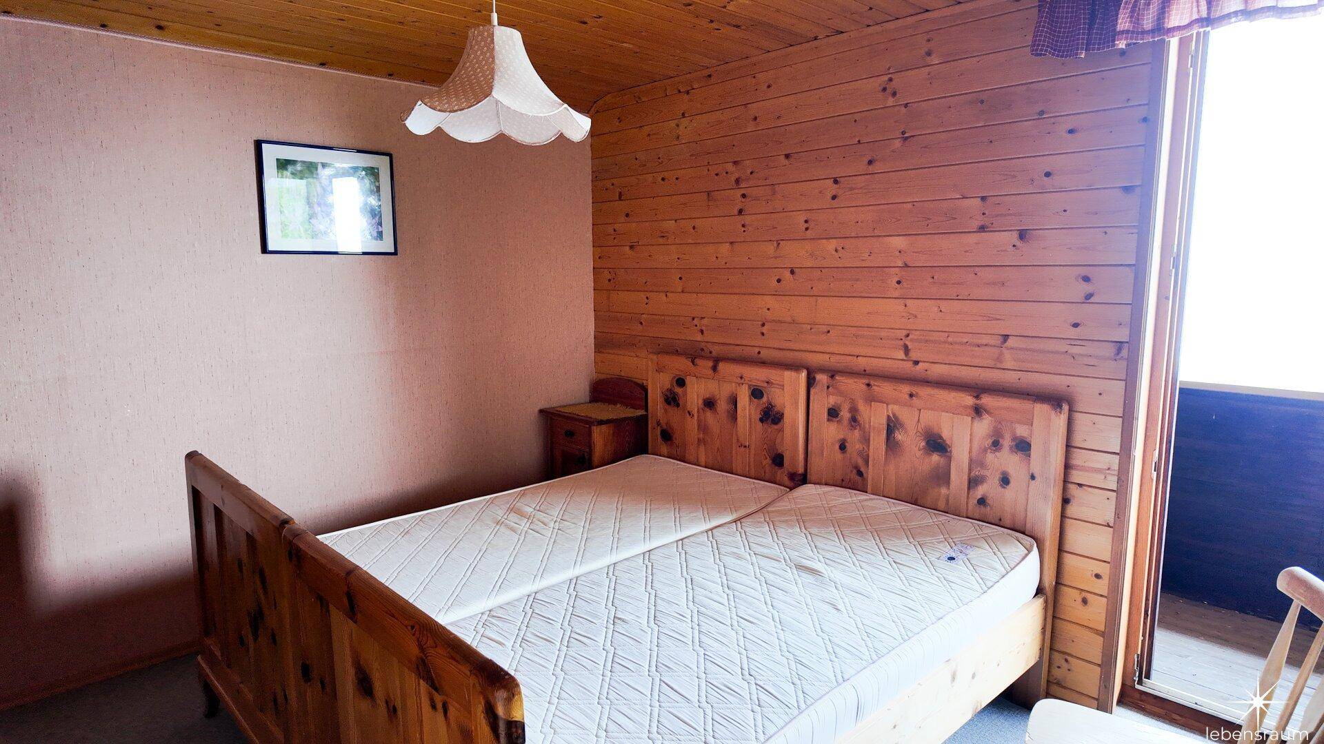Rustikales Schlafzimmer mit Doppelbett, Holzvertäfelung und Zugang zu einem Außenbereich.