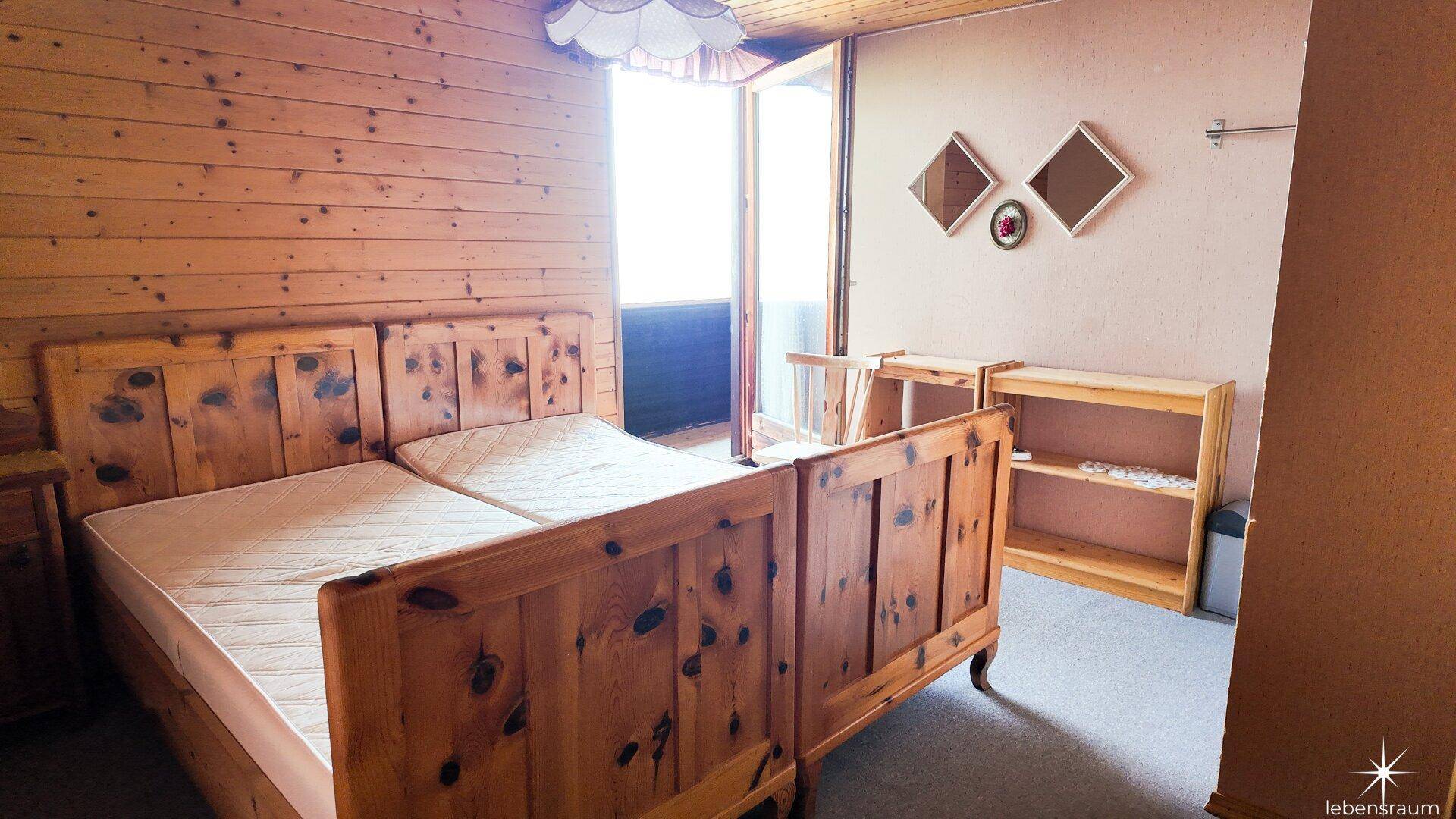 Helles Schlafzimmer mit Doppelbett, Holzvertäfelung und direktem Zugang zu einem Außenbereich.