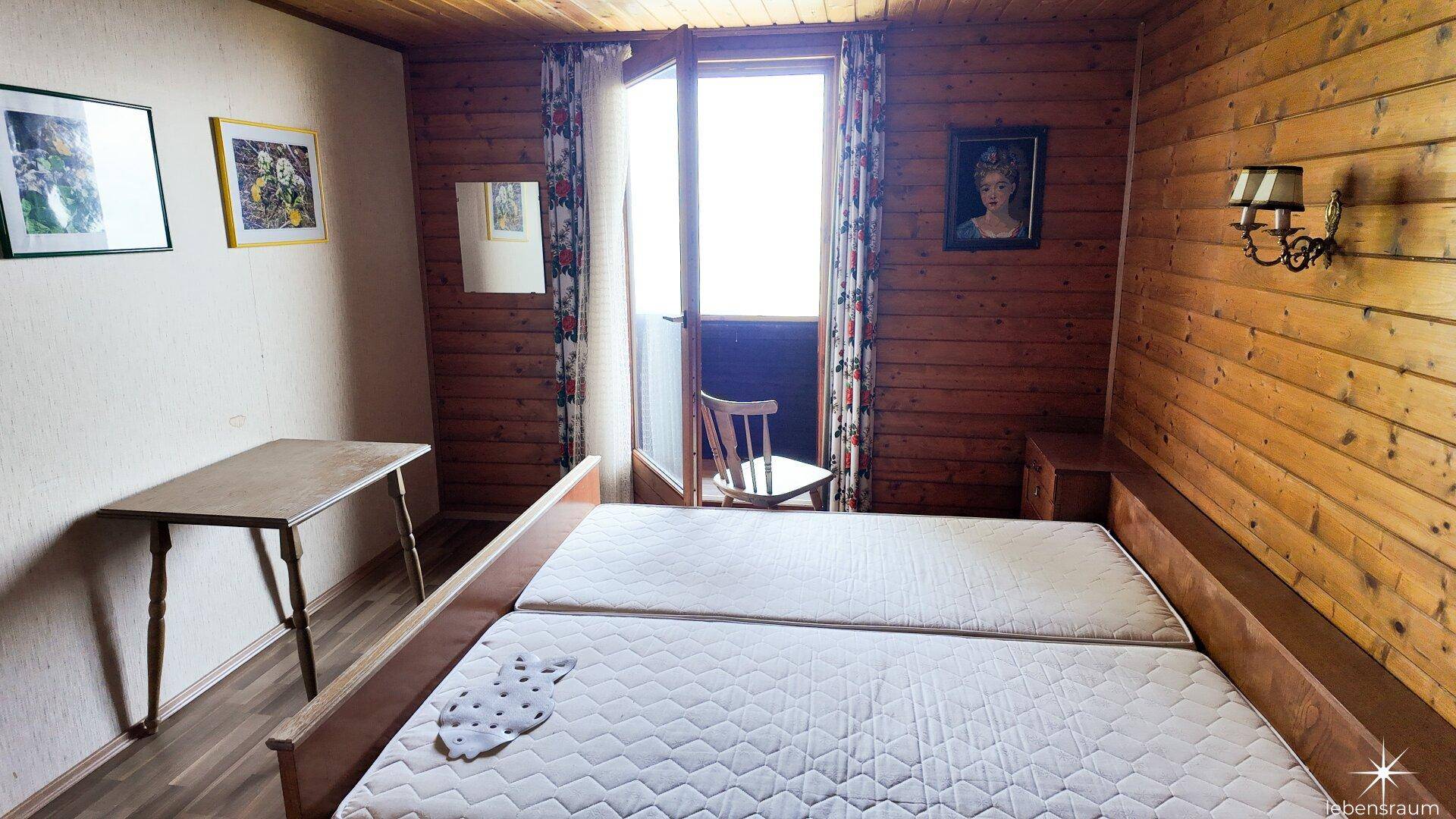 Gemütliches Schlafzimmer mit Doppelbett, Holzwänden und Zugang zu einem Balkon oder einer Terrasse.