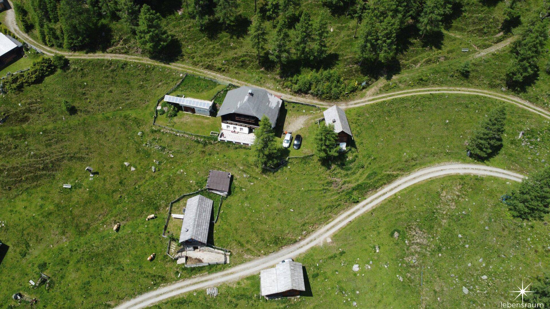 Weitläufige Luftaufnahme des Anwesens in einer idyllischen Berglandschaft mit umliegenden Wegen.