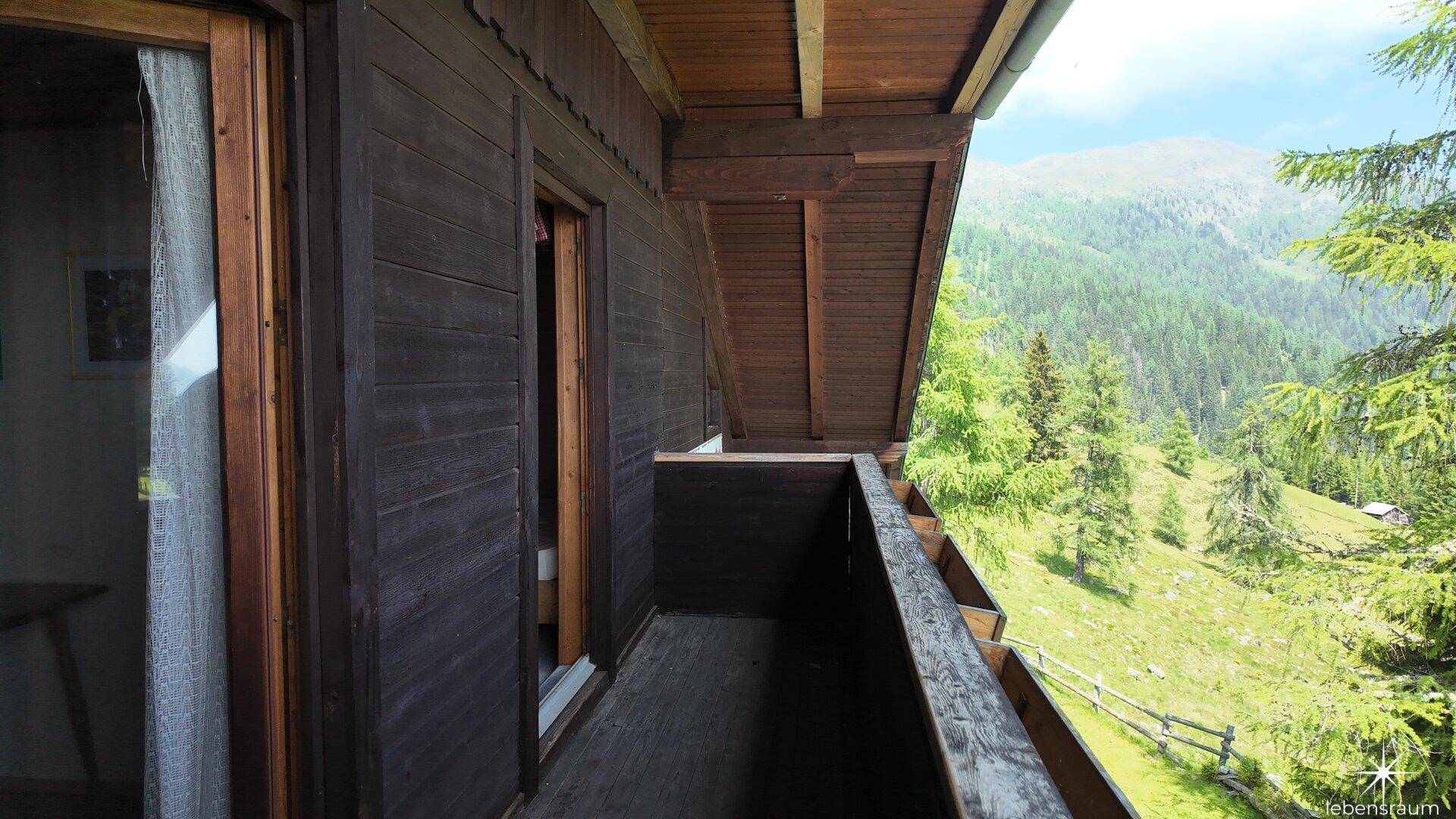 Rustikaler Holzbalkon mit atemberaubendem Blick auf die umliegende grüne Berglandschaft.