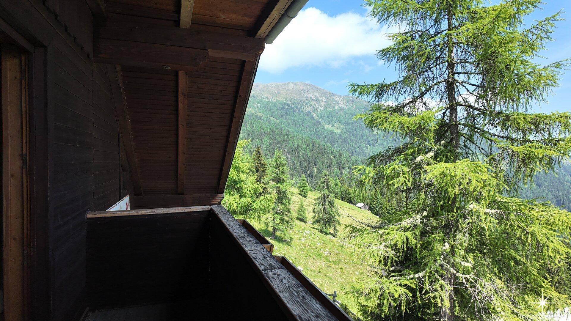 Geräumiger Holzbalkon mit freiem Blick auf die majestätische Bergwelt und dichte Wälder.