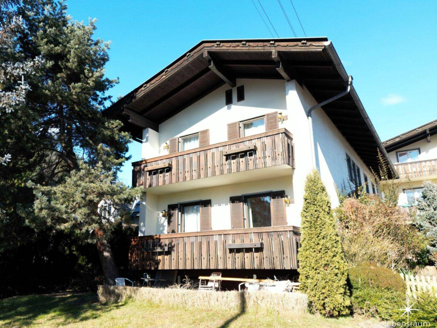 Traditionelles Wohnhaus im Alpenstil mit mehreren Holzbalkonen und gepflegtem Gartenbereich.