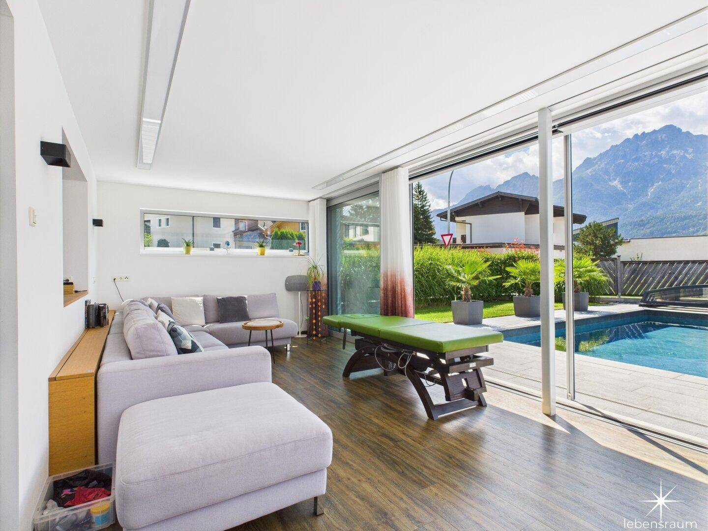 Heller Wohnbereich mit großen Schiebetüren, die zum Pool und den Bergen führen.