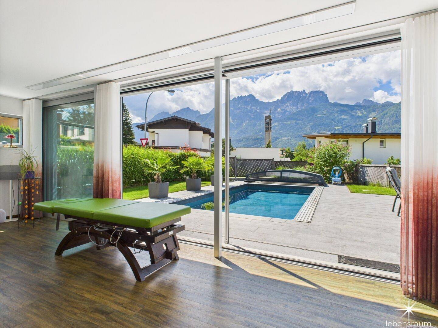 Lichtdurchfluteter Raum mit Panoramablick auf den Pool und die majestätischen Berge.