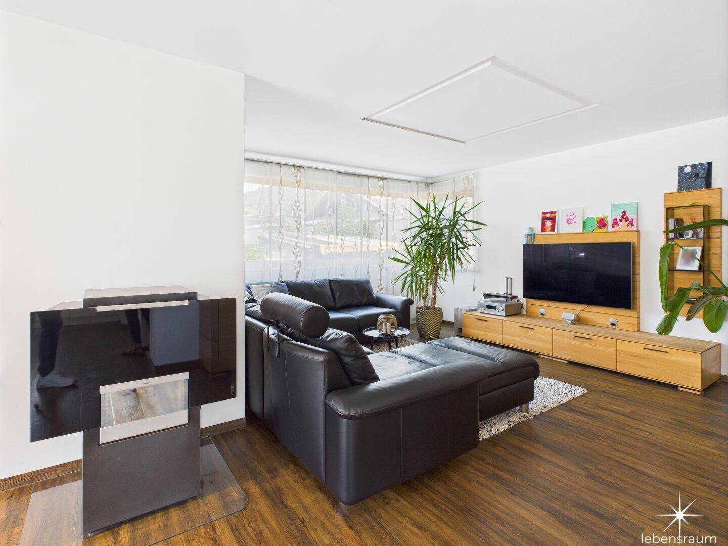Gemütliches Wohnzimmer mit großem Sofa, Holzboden und viel Tageslicht.