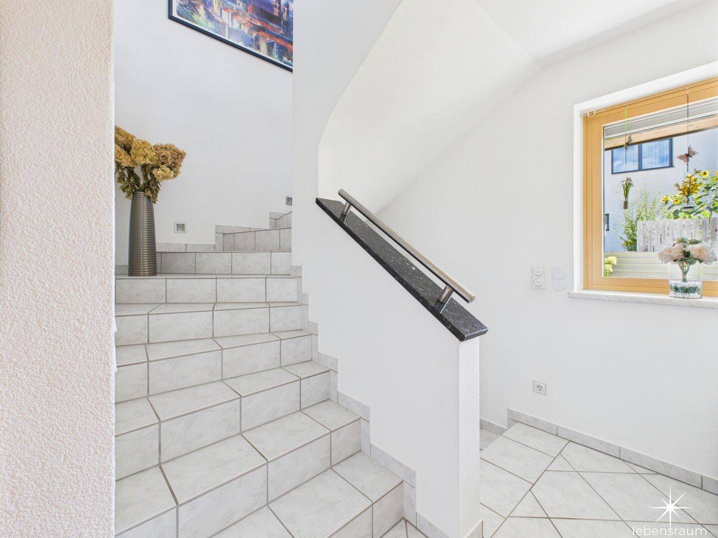 Helles Treppenhaus mit Fliesenstufen und Fenster für natürliches Licht.