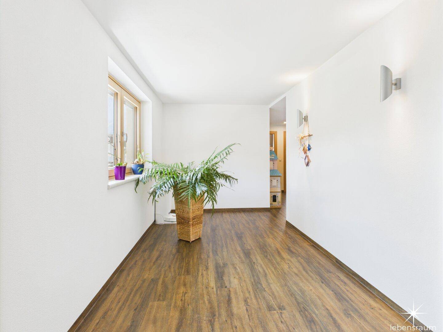 Geräumiger Flur mit Holzboden und großem Fenster, das viel Licht hereinlässt.