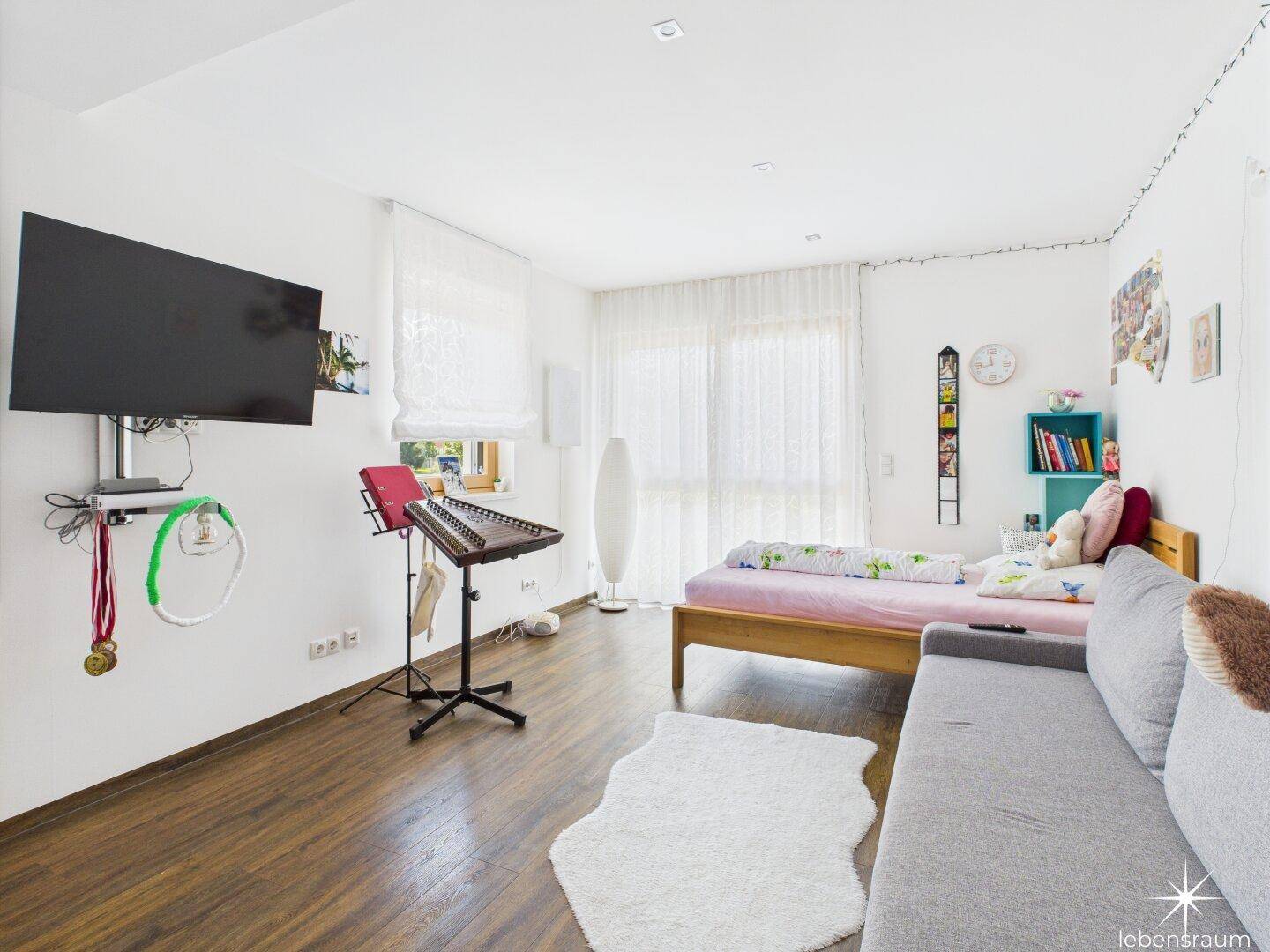 Kinderzimmer mit Holzboden, großem Fenster und moderner Dekoration.