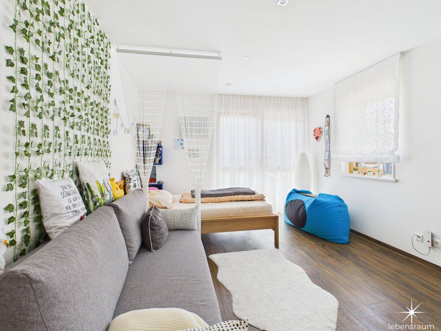 Helles Kinderzimmer mit kreativer Wandgestaltung und viel Tageslicht.