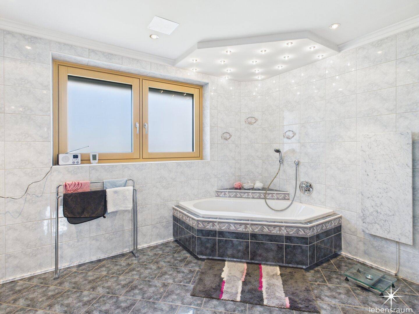 Geräumiges Badezimmer mit Eckbadewanne, Fliesenboden und Fenster.