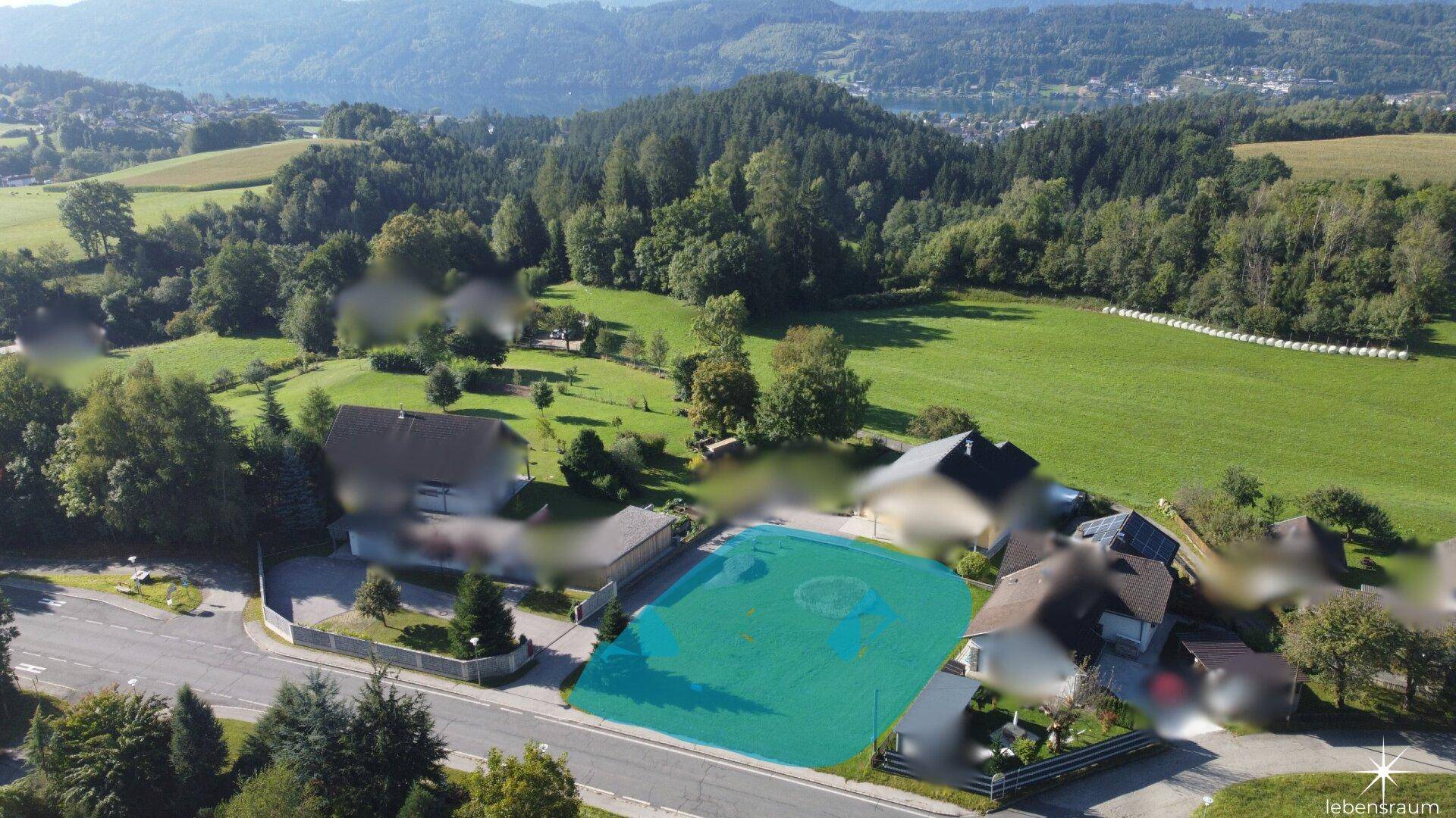 Weitläufige Luftaufnahme des Baugrundstücks in ländlicher Umgebung mit Bergblick.