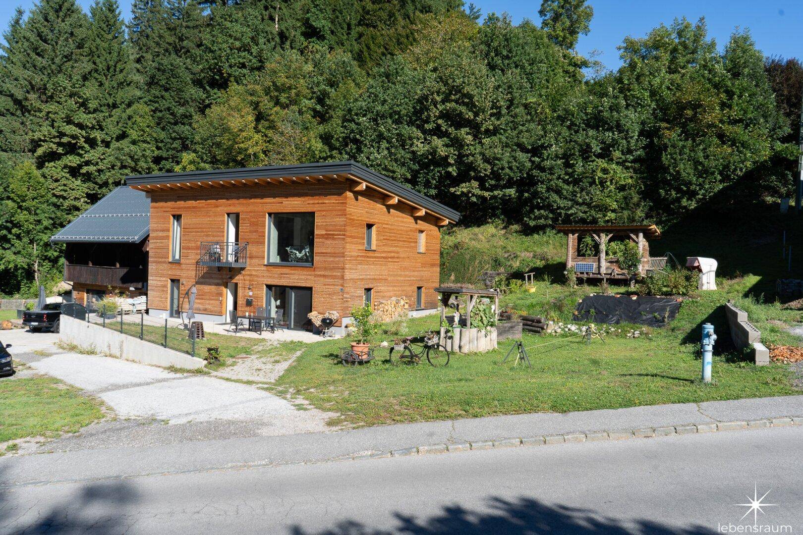 Zwei Häuser mit gepflegtem Garten, Rasenfläche und einem charmanten Holzpavillon.