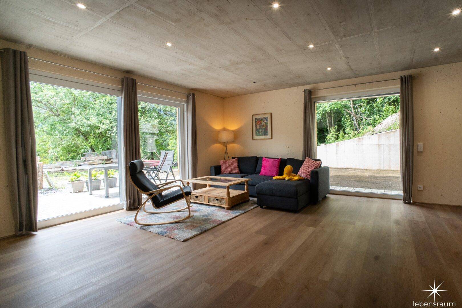 Geräumiges Wohnzimmer mit Holzboden, Sofa und Zugang zur Terrasse.