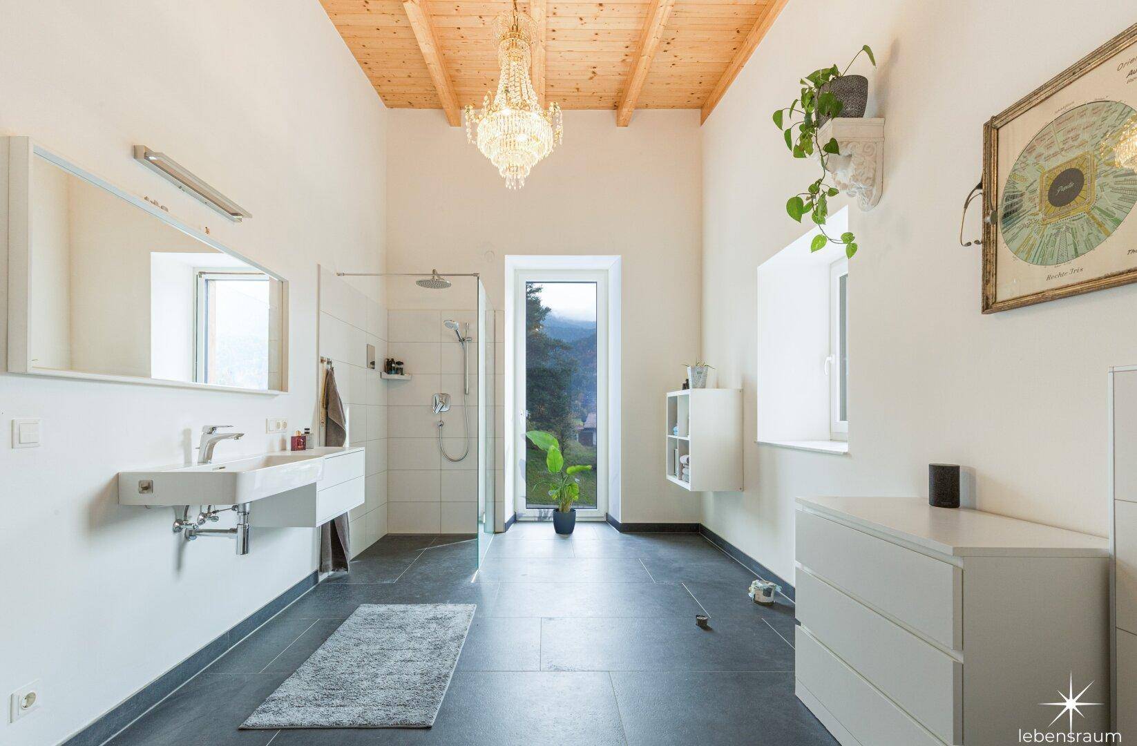 Helles Badezimmer mit begehbarer Dusche, großem Fenster und Holzdecke.