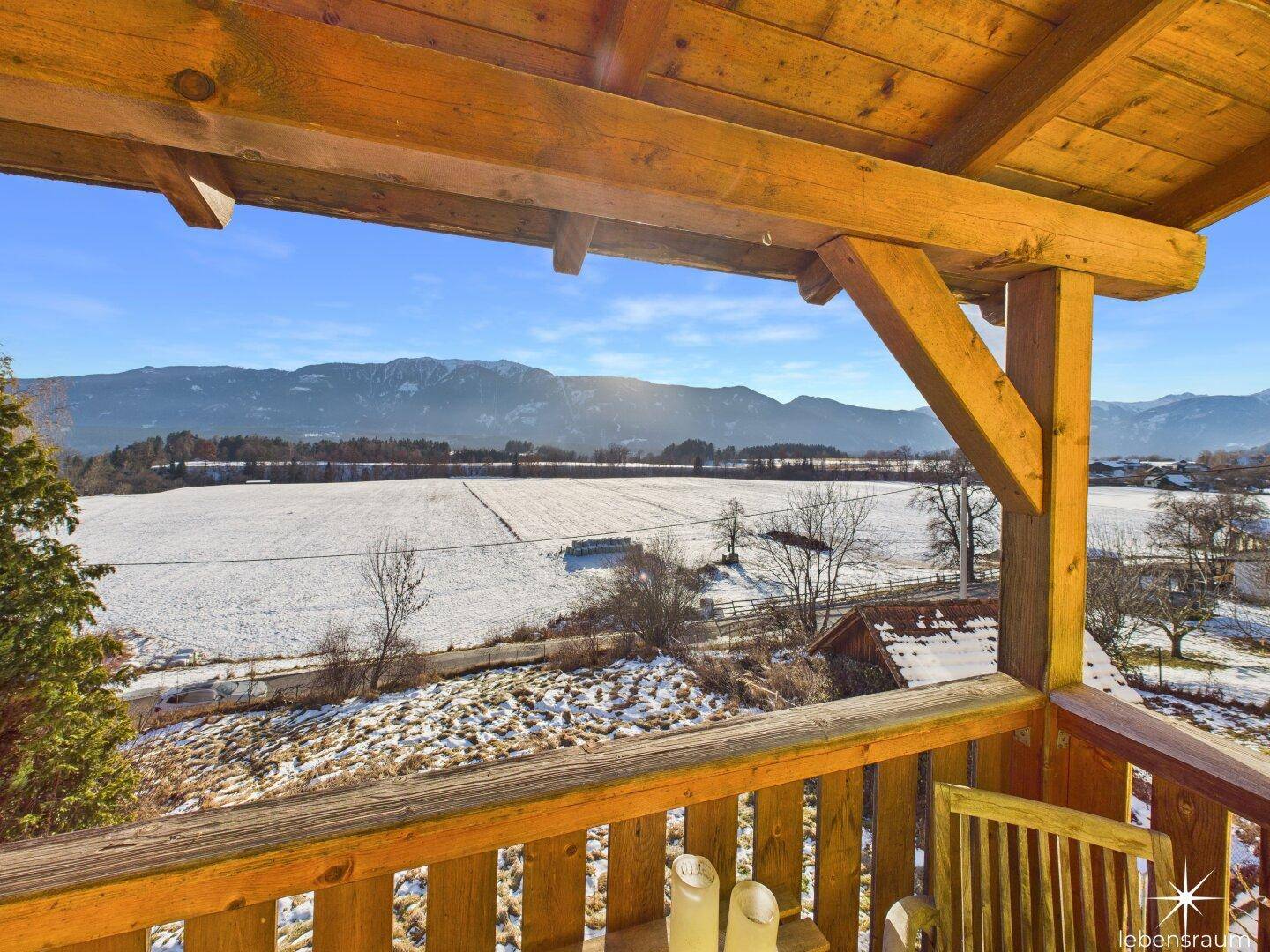Geräumiger Holzbalkon mit Panoramablick auf die schneebedeckten Felder und Berge, ideal zum Entspannen.