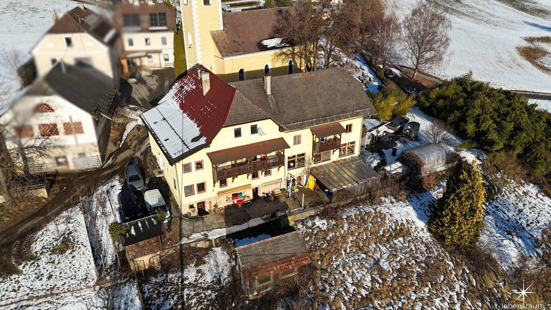 Luftaufnahme des Anwesens mit umliegenden Gebäuden und verschneiter Landschaft, idyllische Umgebung.