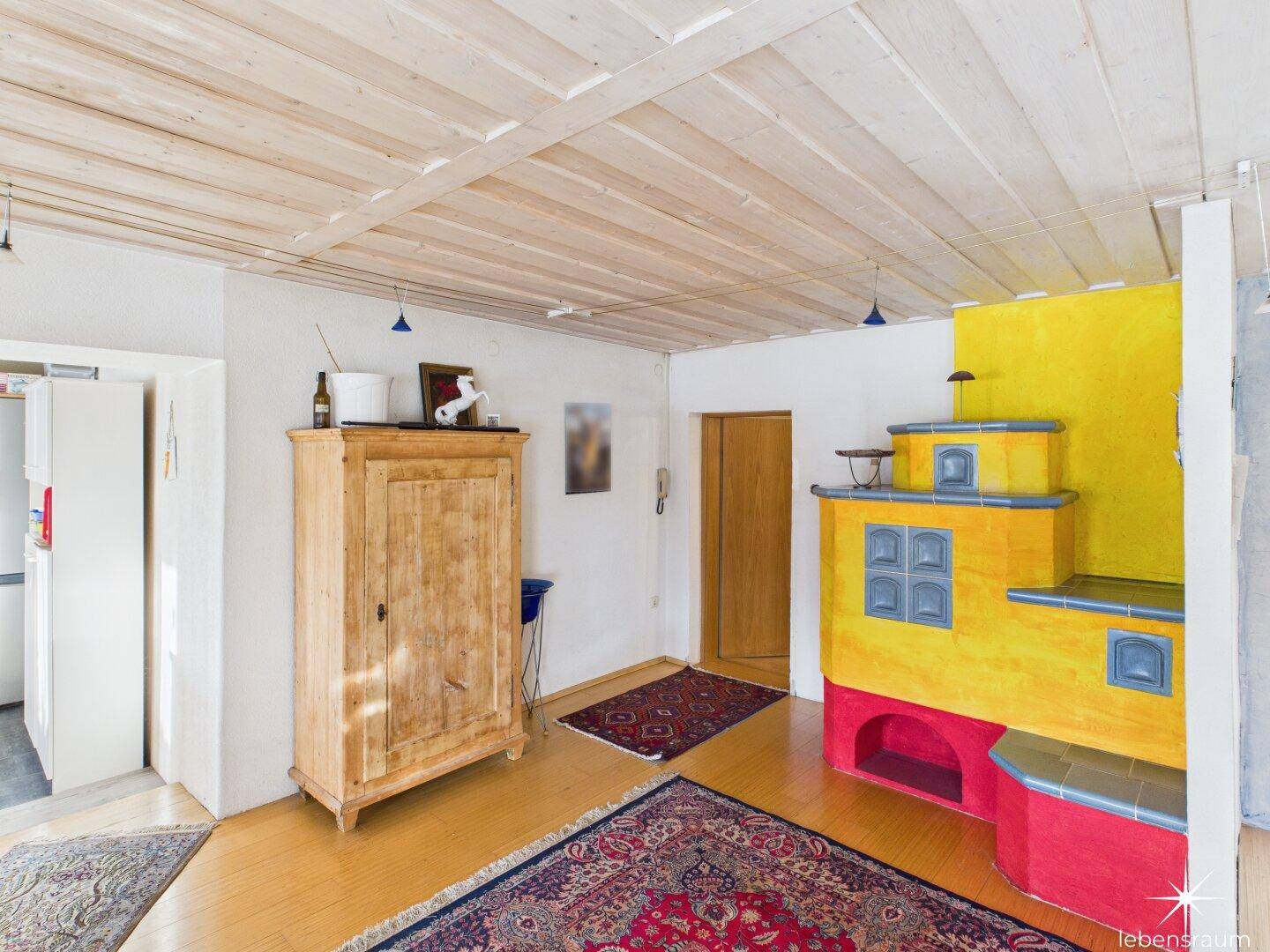Eingangsbereich mit traditionellem Kachelofen, Holzschrank und Teppichboden, schafft eine warme Atmosphäre.