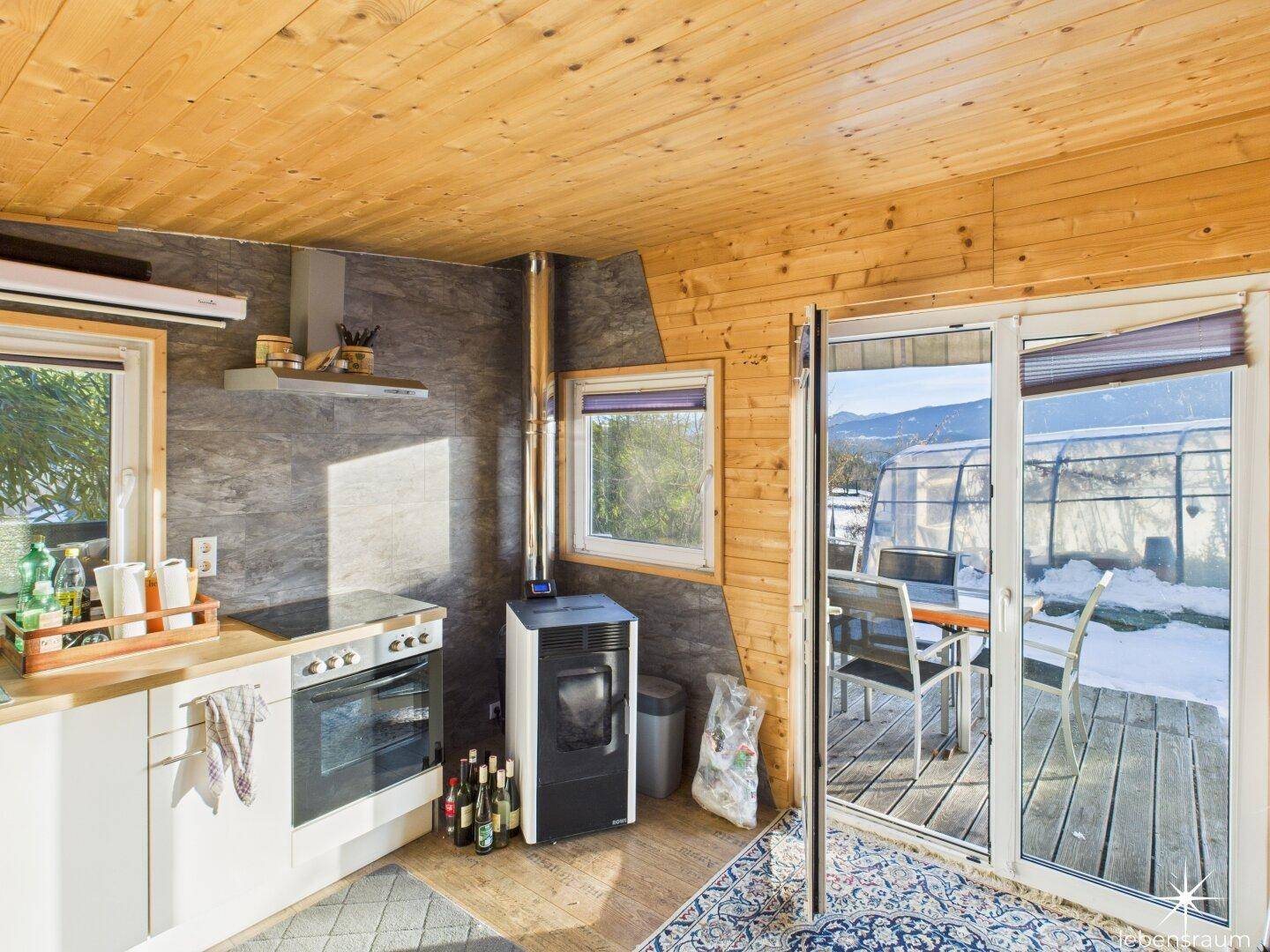 Kleine Küchenzeile in einem Holzhaus mit Pelletofen und Zugang zur Terrasse, gemütlich und funktional.