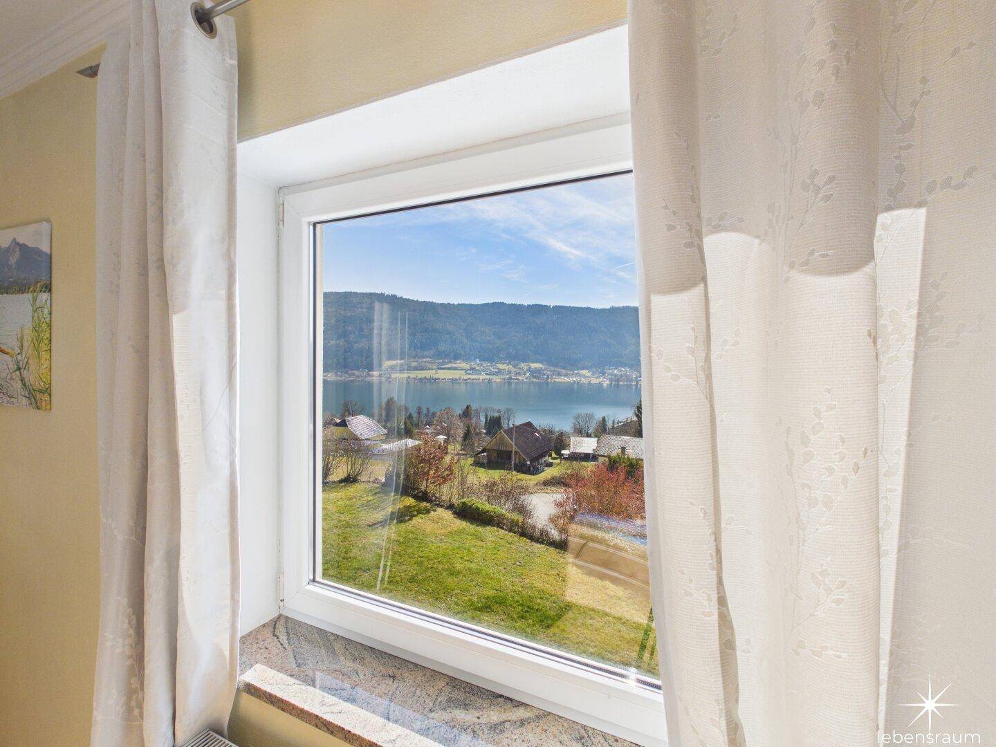 Weitblick aus dem Fenster über den See und die umliegende Berglandschaft.