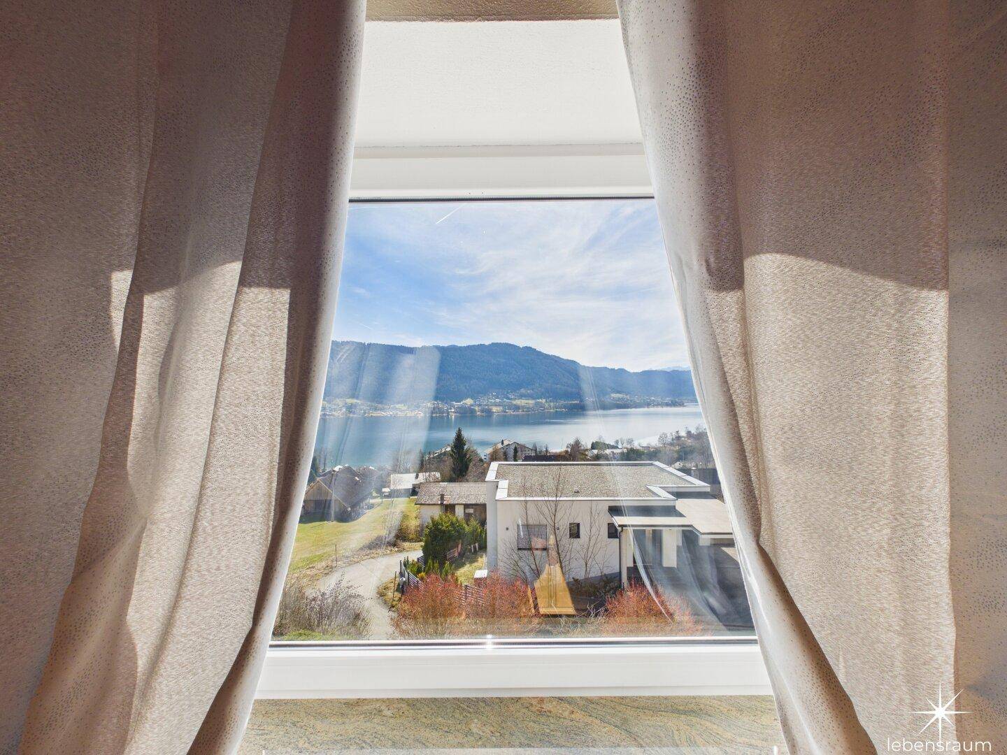 Weitblick aus dem Fenster über den See und die umliegende Berglandschaft.
