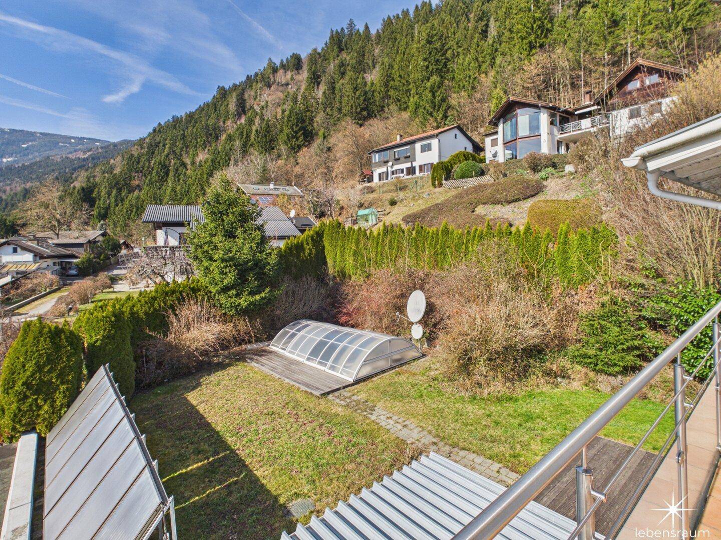Gepflegter Gartenbereich mit überdachtem Pool und Blick auf die bewaldeten Hügel.