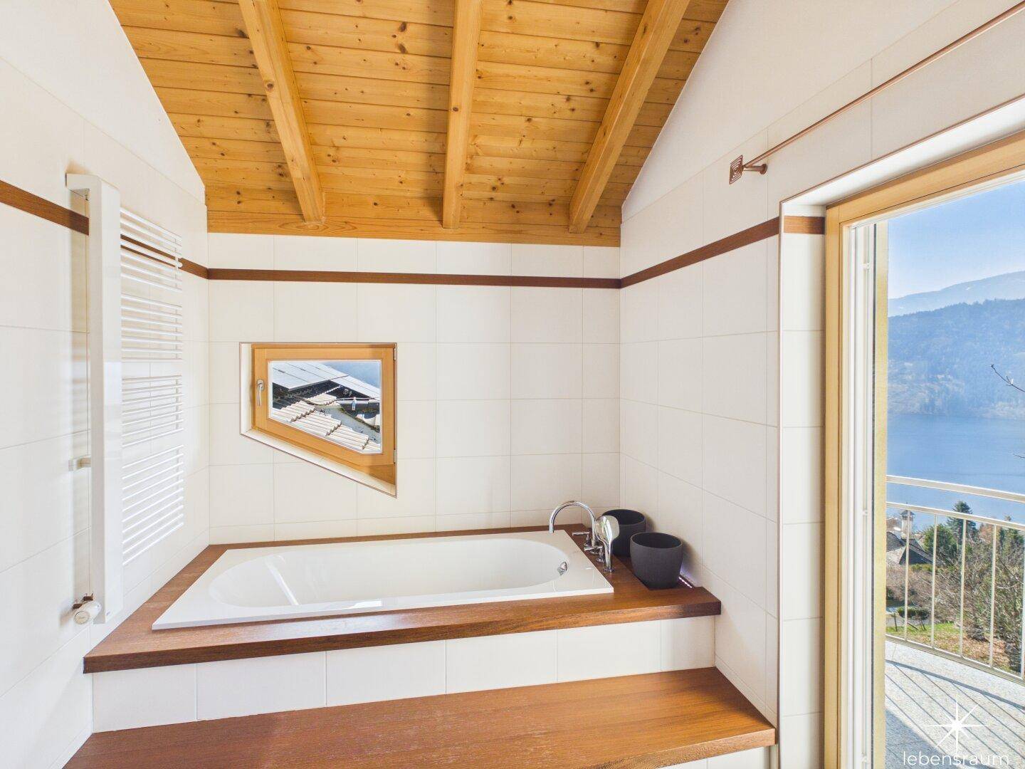 Badezimmer mit Badewanne, Holzverkleidung und schräger Decke mit Dachfenster.