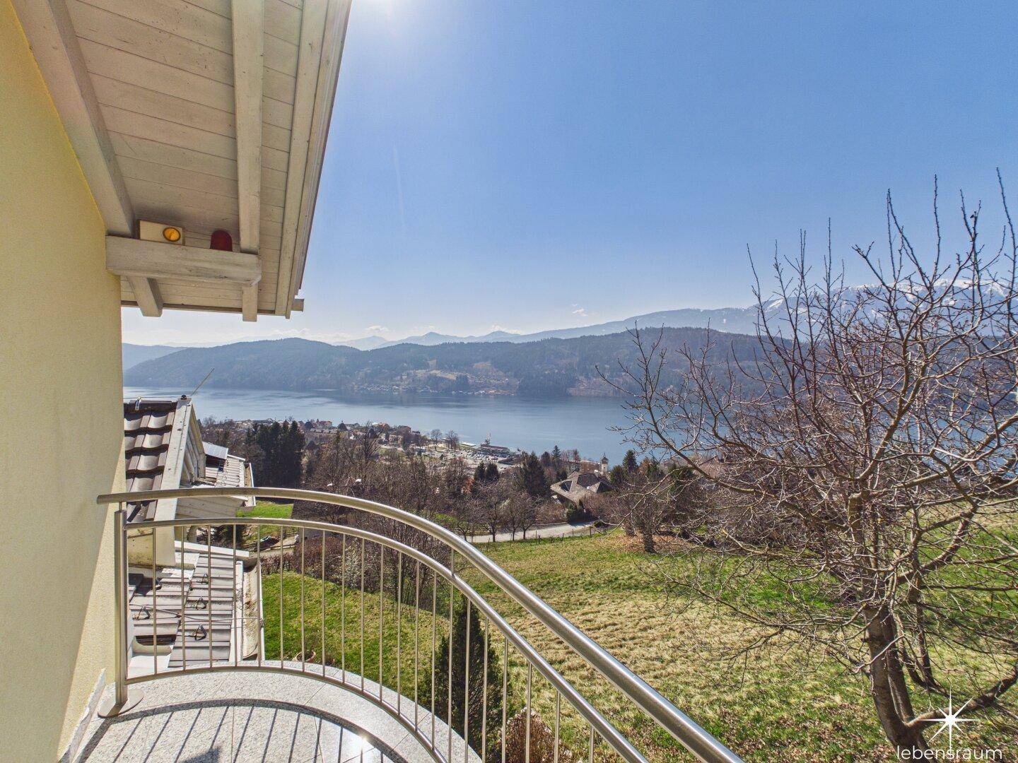 Runder Balkon mit Edelstahlgeländer und herrlichem Blick auf den See und die Berge.