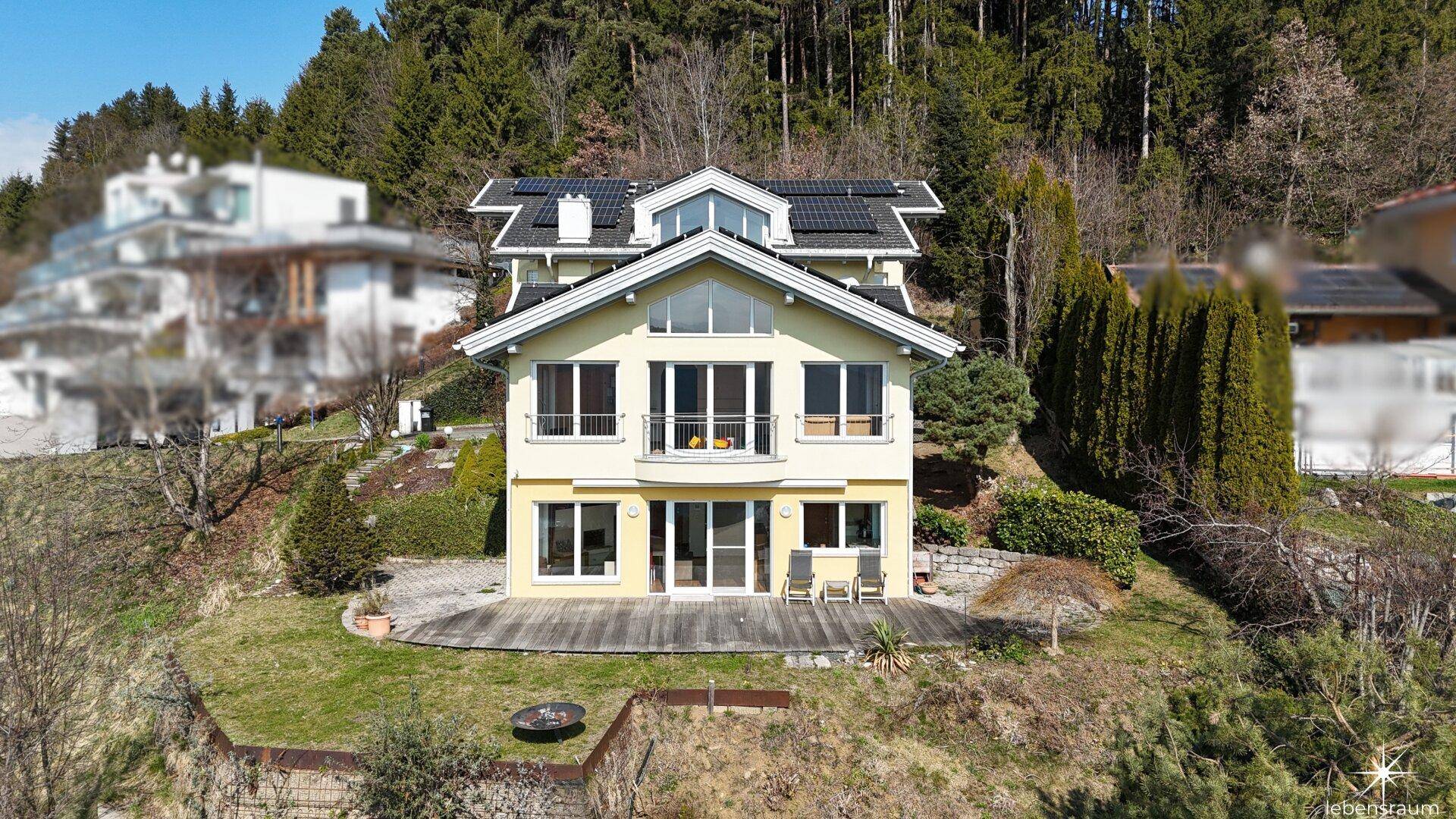 Frontansicht des Hauses mit Solaranlage auf dem Dach und weitläufiger Terrasse im Vordergrund.