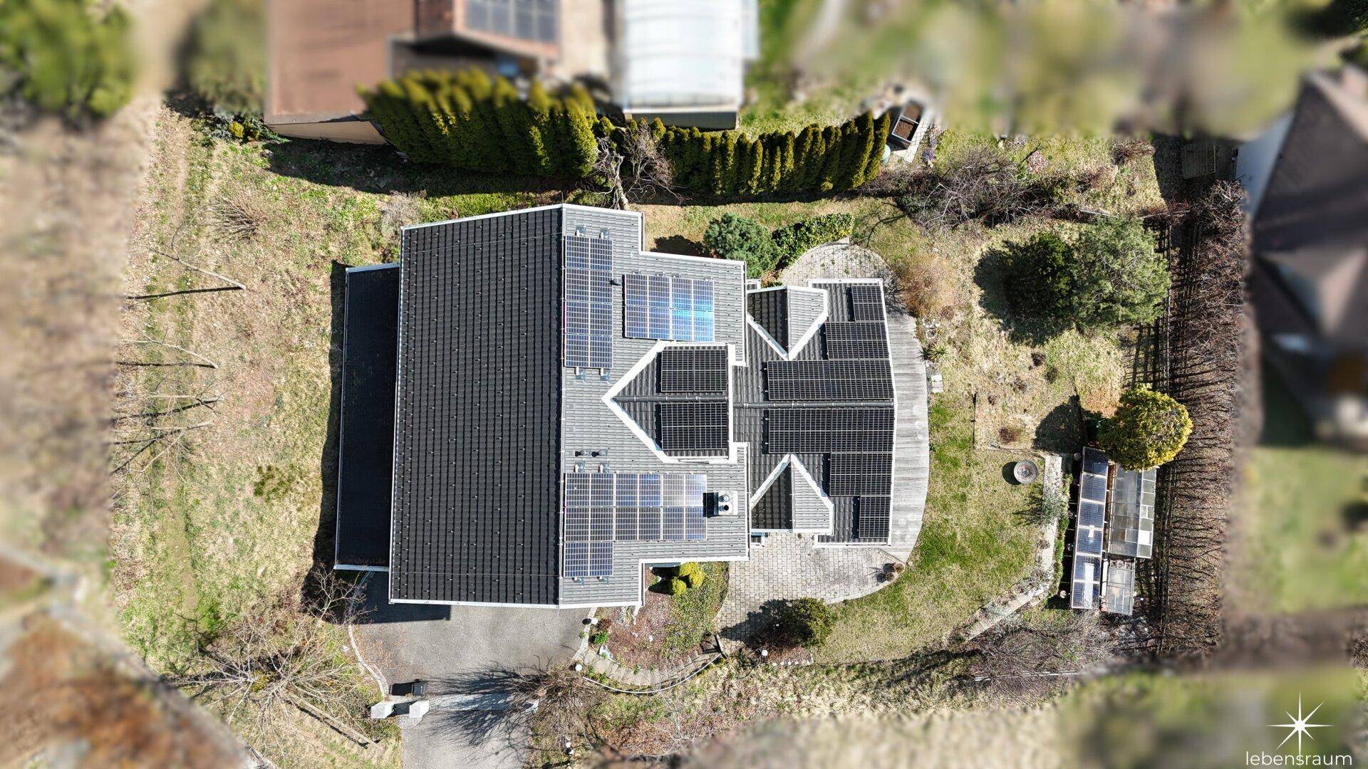 Luftaufnahme des Hauses mit Solaranlage auf dem Dach und umliegendem Grundstück.