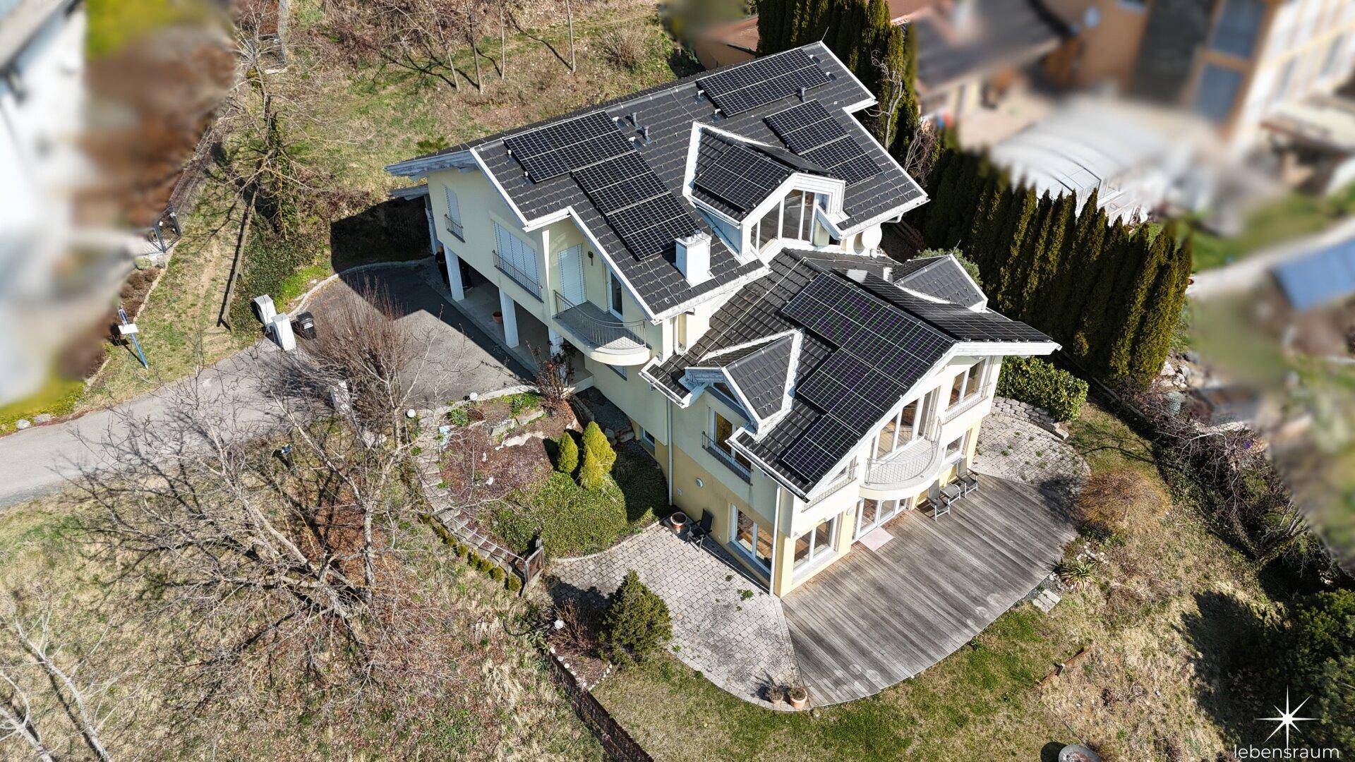 Schrägansicht des Hauses von oben mit Solaranlage, Terrasse und Blick auf die Umgebung.