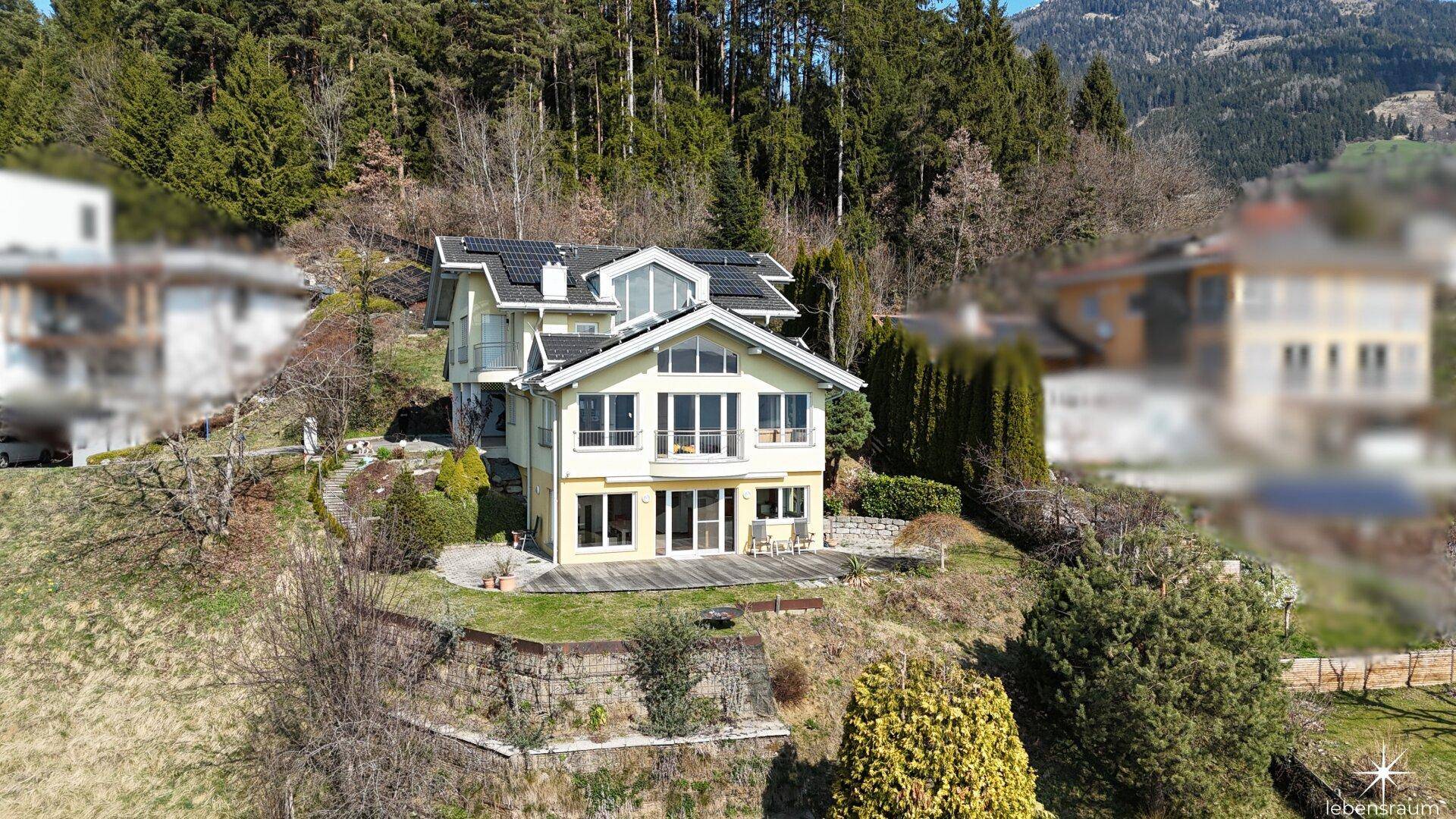 Haus in Hanglage mit Solaranlage, umgeben von Wald und mit Blick auf den See.