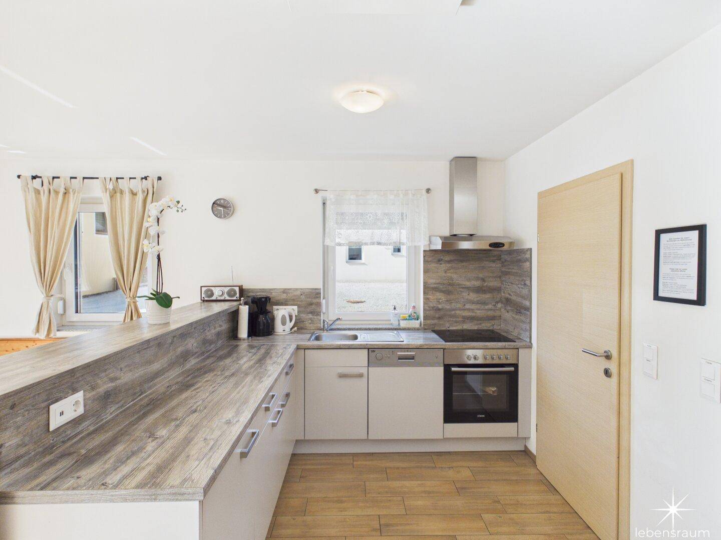 Funktionale Küche mit Holz-Arbeitsplatten, integrierten Geräten und Fenster für Tageslicht.