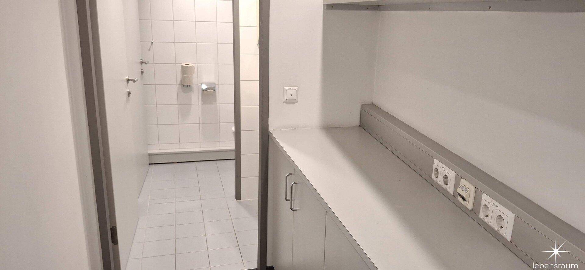 Praktischer Abstellraum mit Arbeitsplatte und Waschbecken, angrenzend an einen gefliesten Bereich.