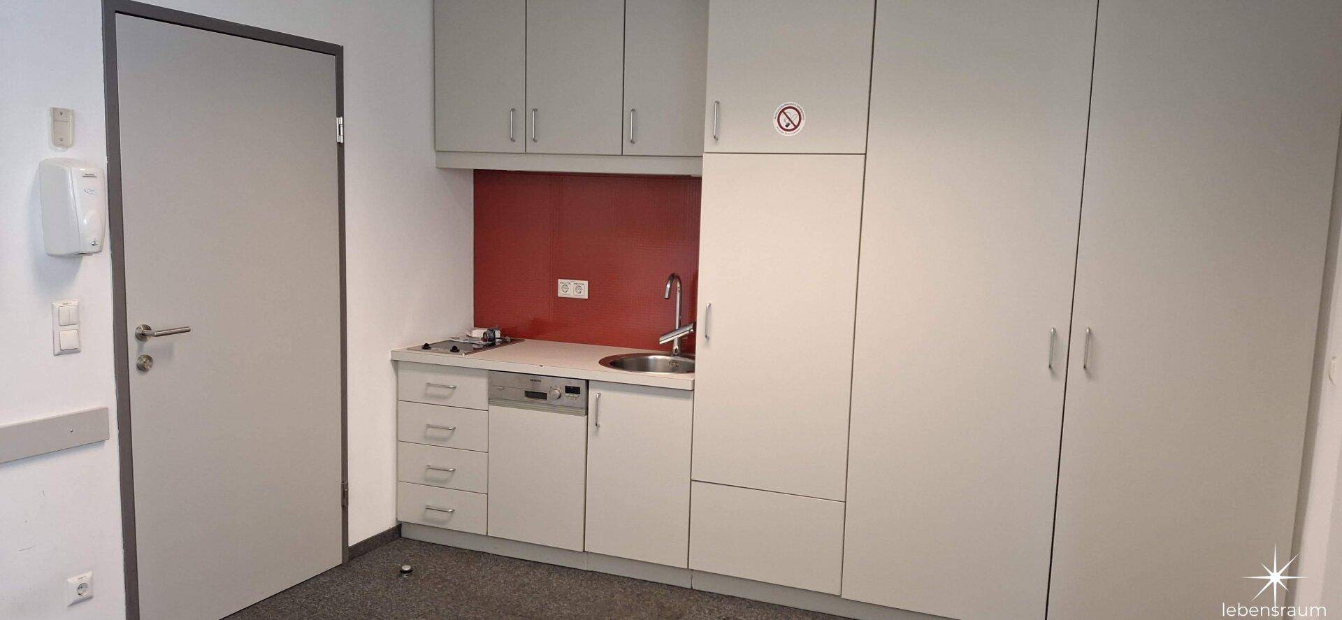 Funktionale Küchenzeile mit Spülbecken, Kochfeld und Stauraum, perfekt für kleine Büros.