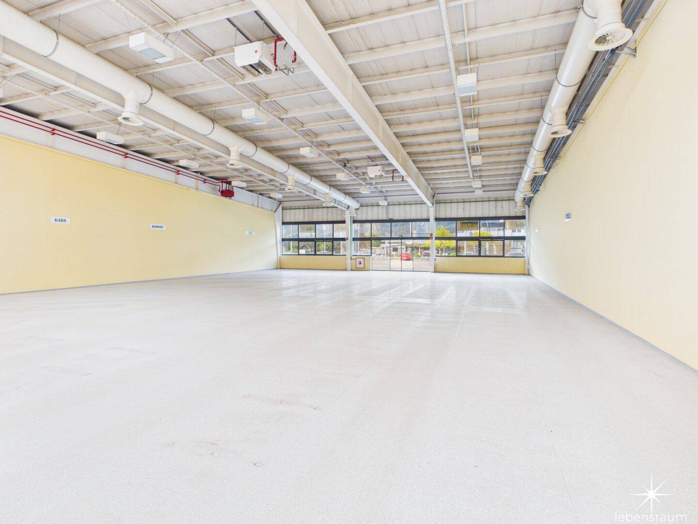 Weitläufiger, heller Gewerberaum mit großen Fenstern, hohen Decken und industrieller Ästhetik.