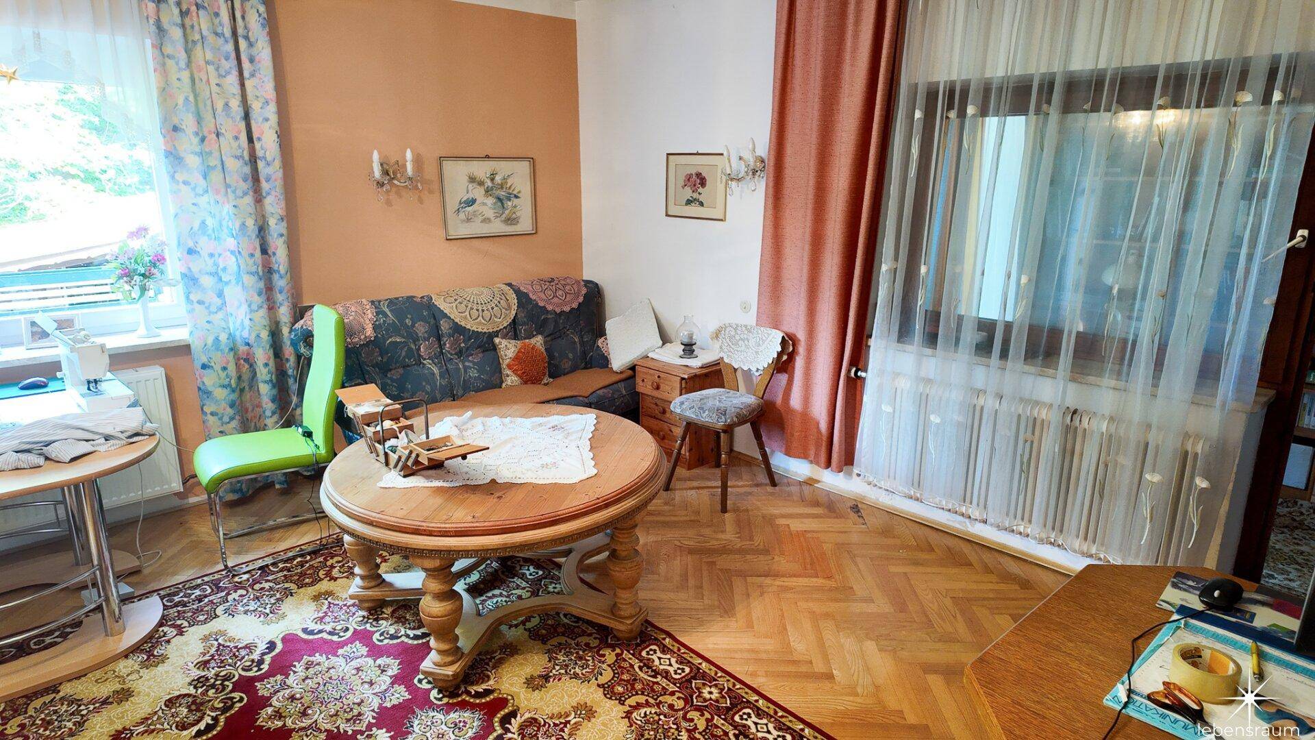 Gemütliches Wohnzimmer mit Fischgrätparkett, traditionellem Teppich und bequemer Couch.