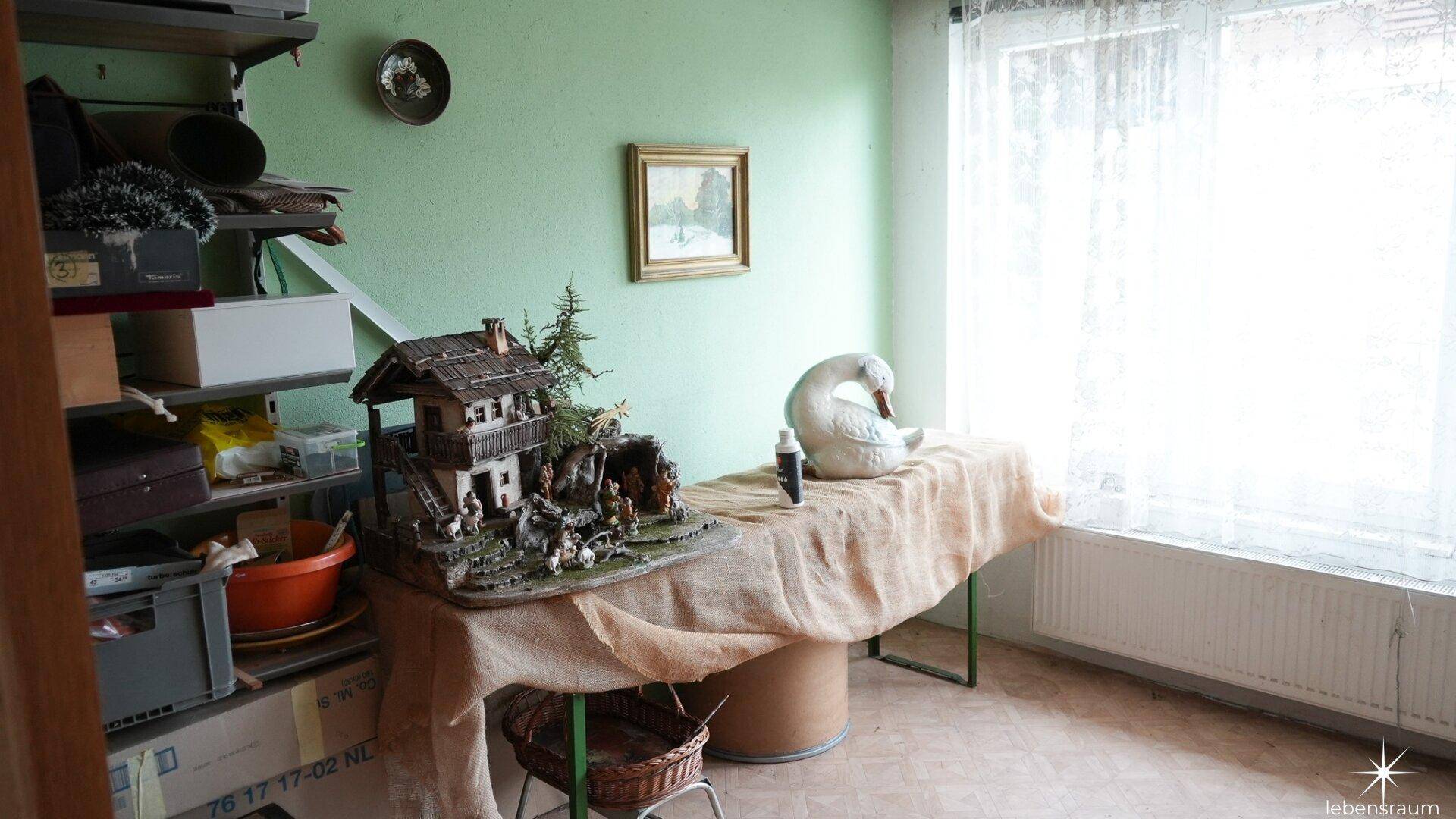 Einfacher Abstellraum mit Regalen, grün gestrichenen Wänden und einem Fenster.