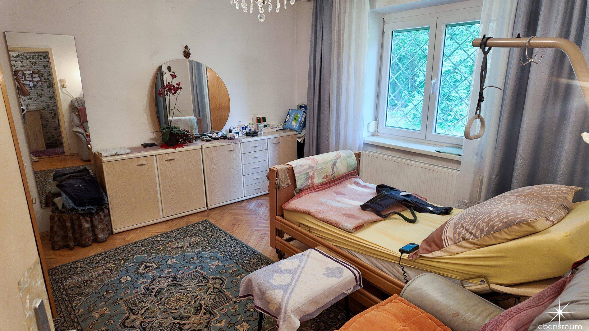 Geräumiges Schlafzimmer mit Holzboden, großem Spiegel und Fenster mit Vorhängen.