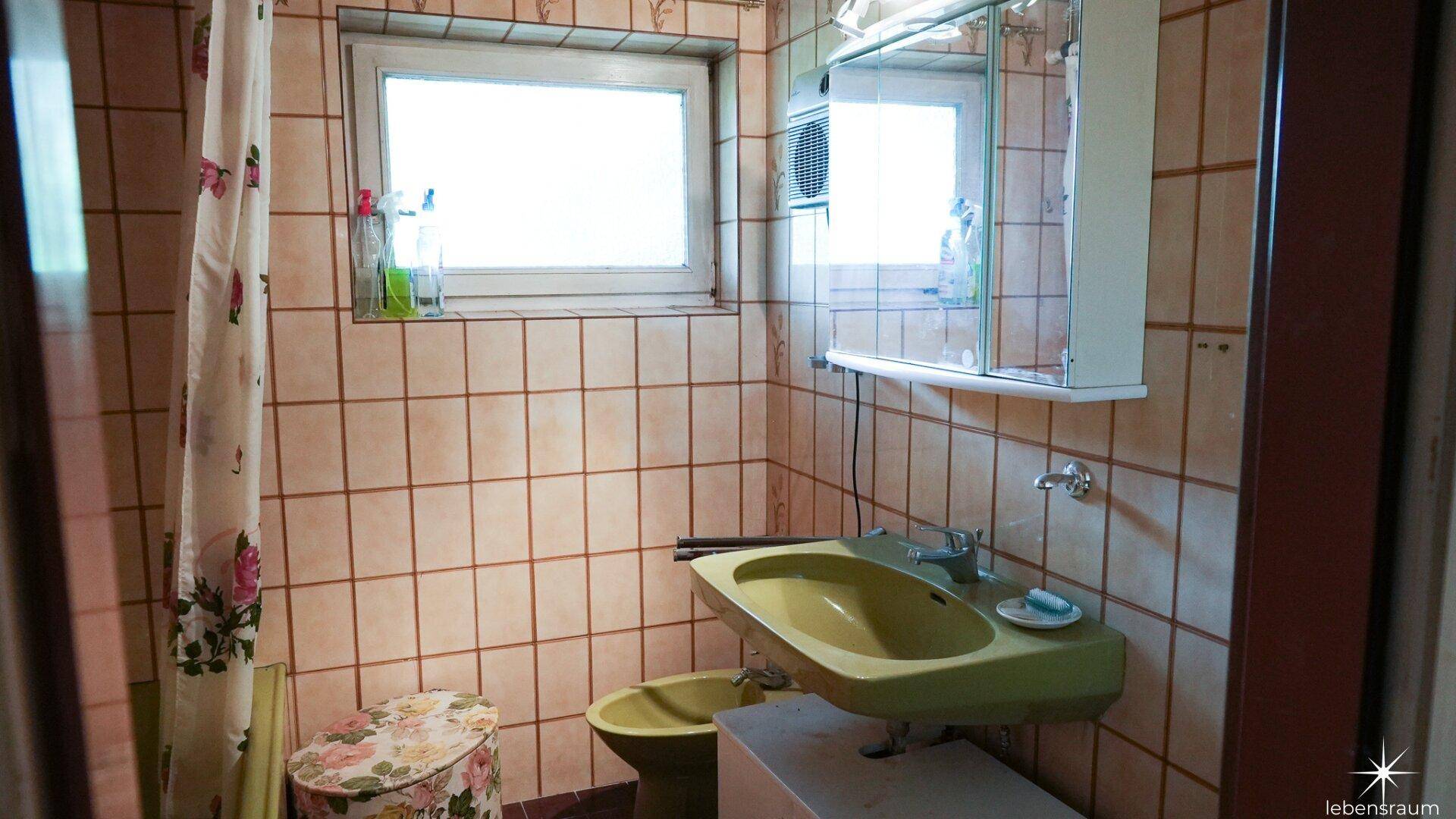 Badezimmer mit gelben Fliesen, Waschbecken, WC und Fenster für Tageslicht.