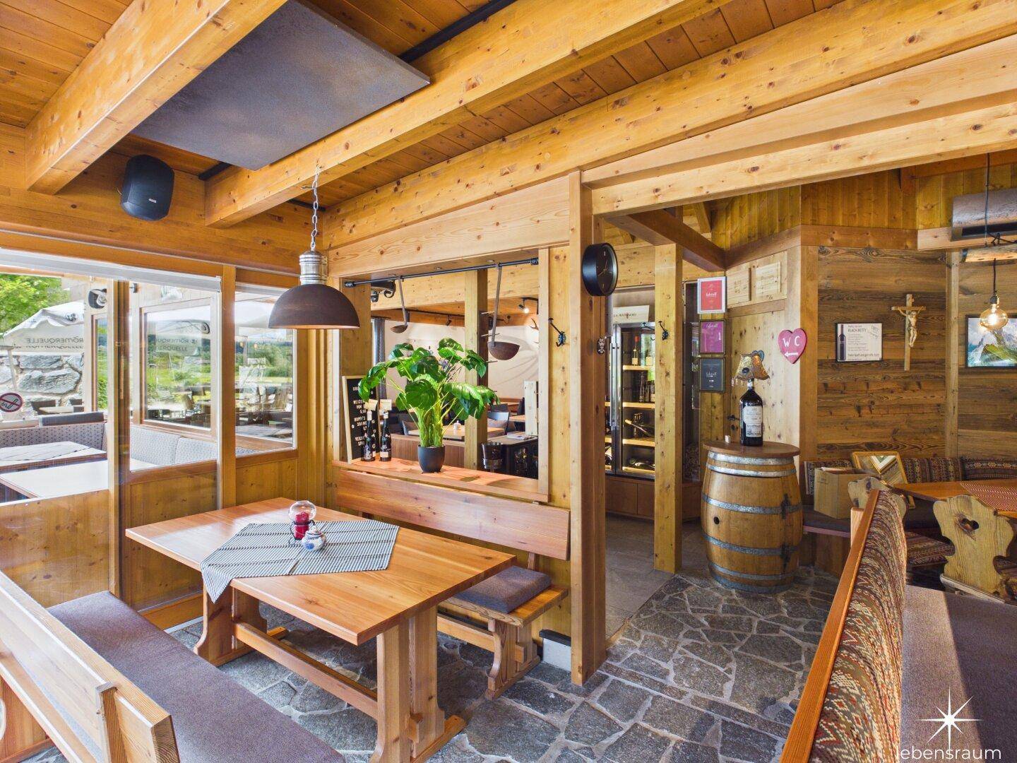 Gemütlicher Restaurantbereich mit Holzbalken, Steinboden und traditionellen Sitzgelegenheiten.